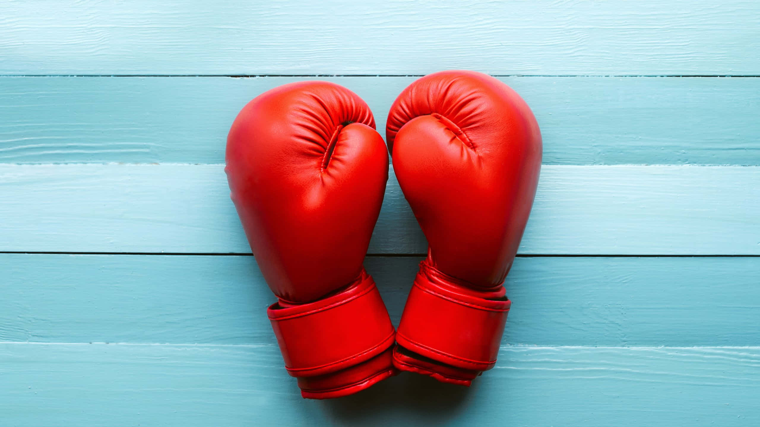 red boxing gloves, blue background, weathered light blue wooden surface, 2K Desktop Wallpaper