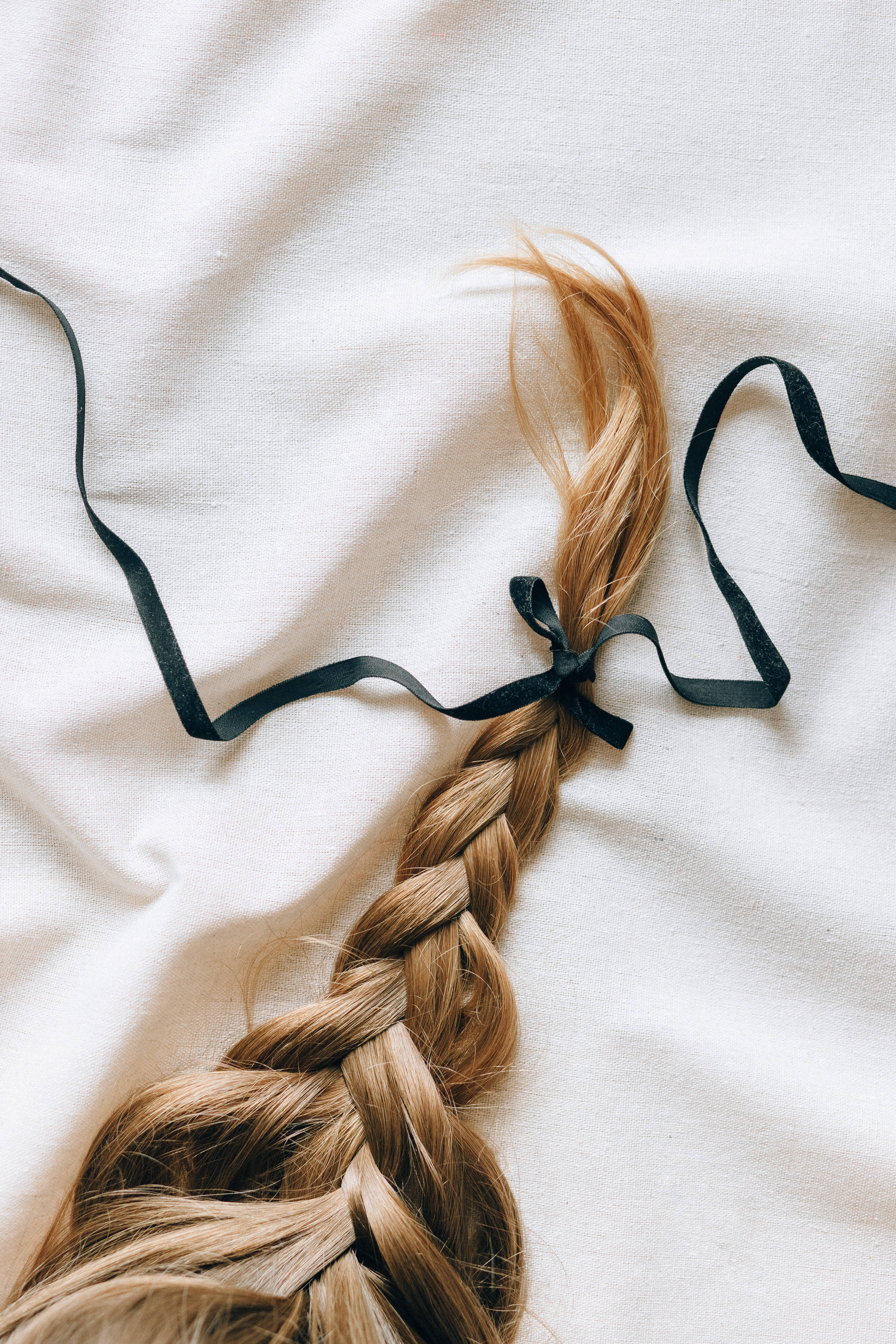 golden-brown braided hair, black ribbon, soft white fabric surface, 5K Phone Wallpaper