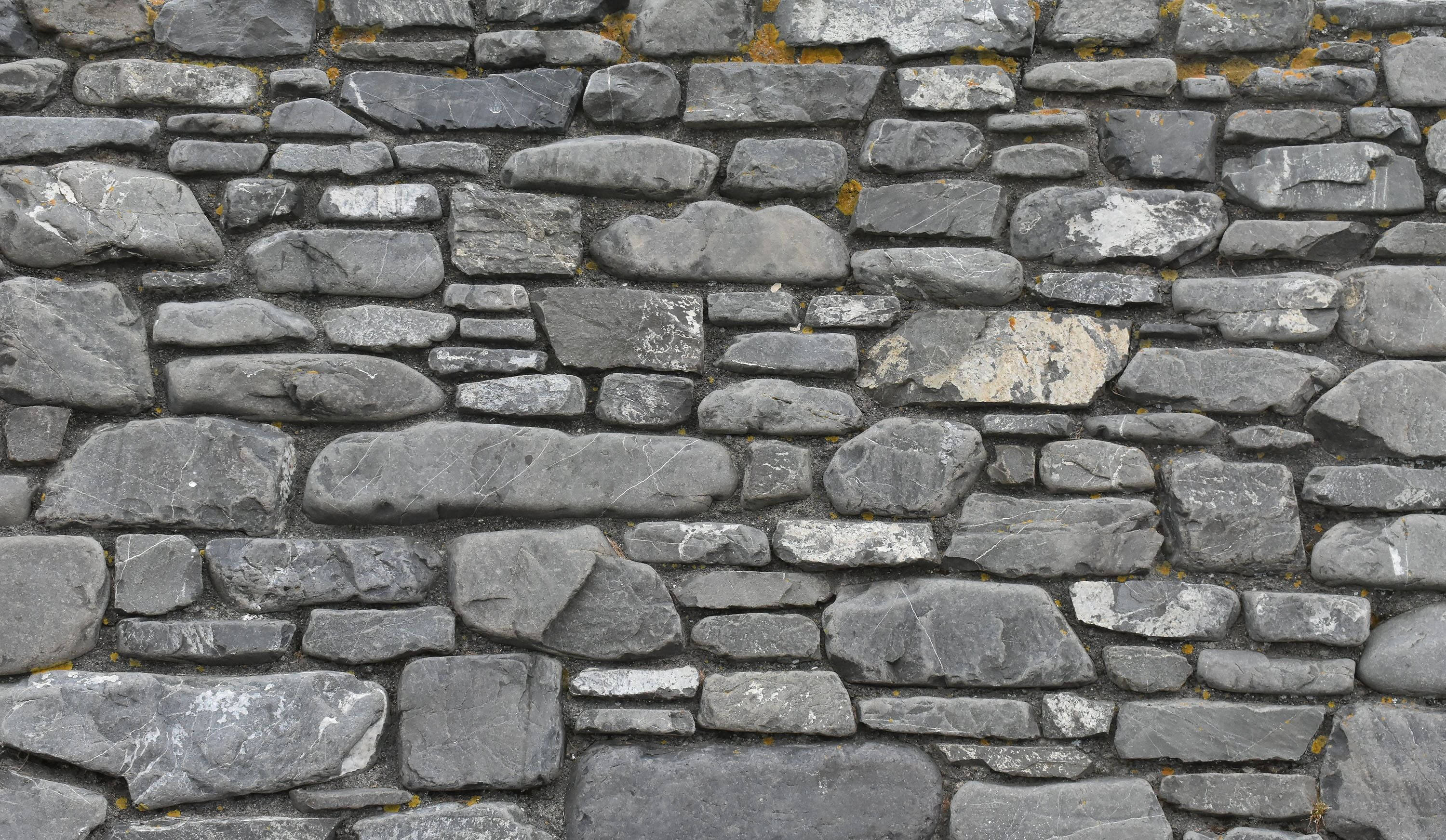 protruding brick wall, rugged gray stone wall, mossy patches, 2K Desktop Wallpaper