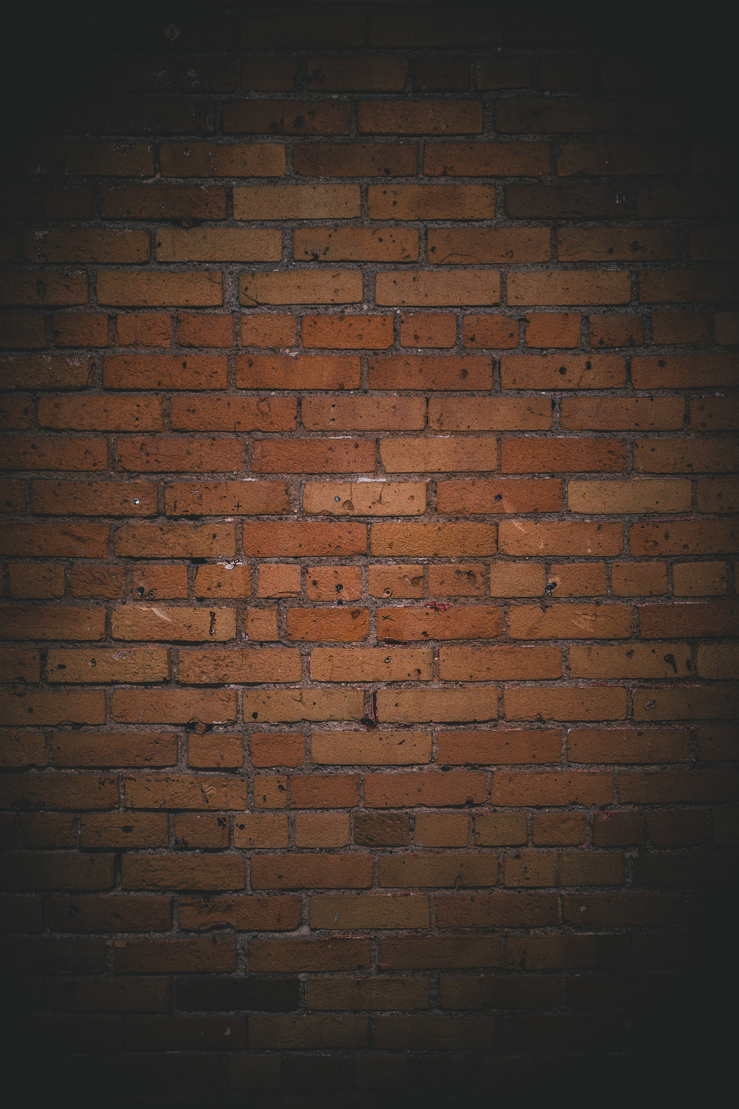 dark rusty brown brick wall, warm orange tones, dark shadows, 2K Phone Wallpaper