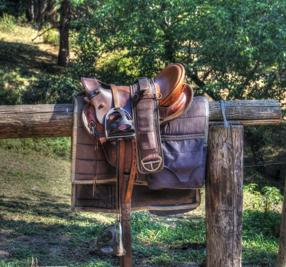 brown leather Western saddle, rustic wooden fence post, sunlit grassy field, SD Desktop Wallpaper