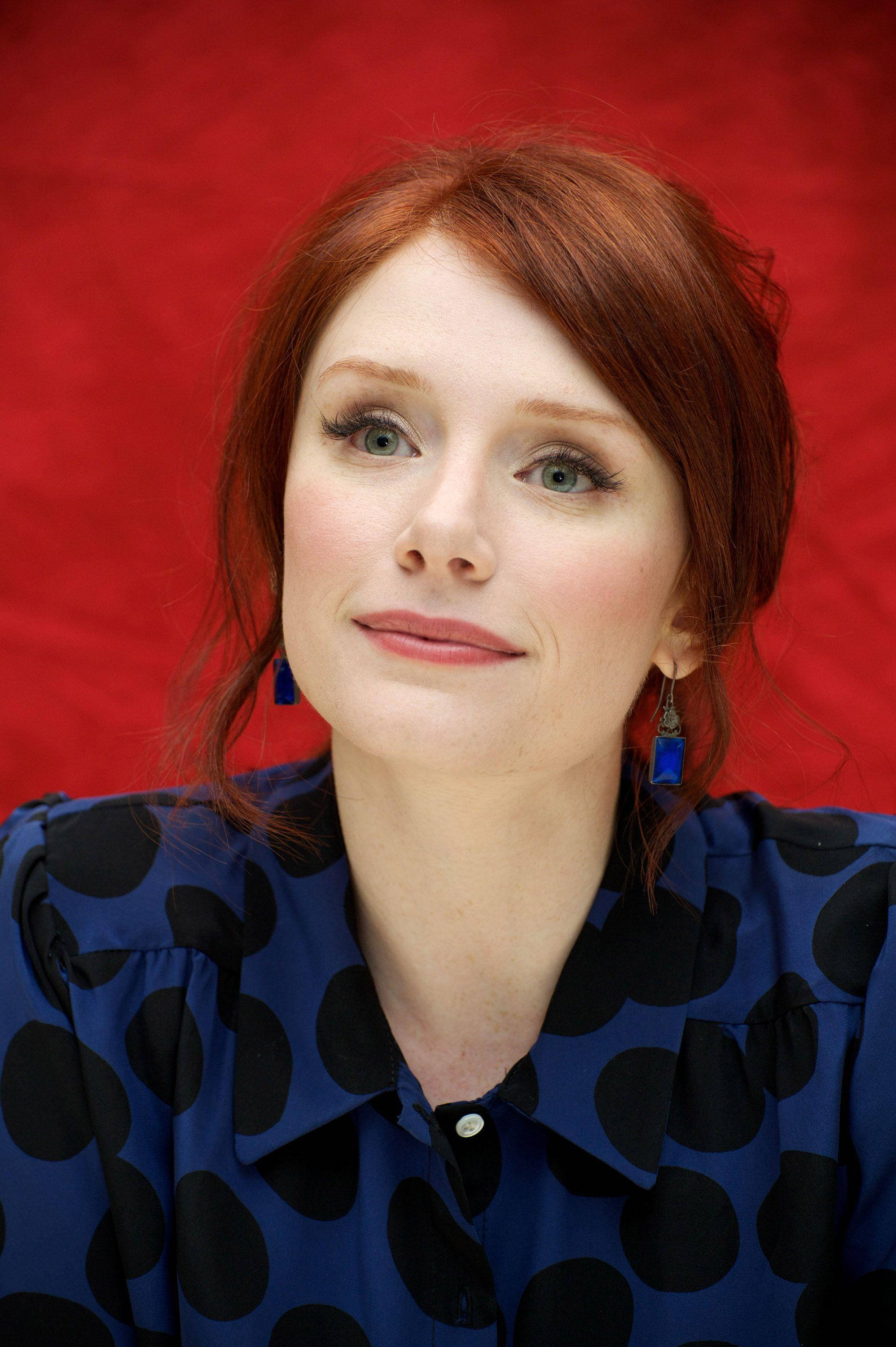 Bryce Dallas Howard, blue blouse with black polka dots, red backdrop, 2K Phone Wallpaper