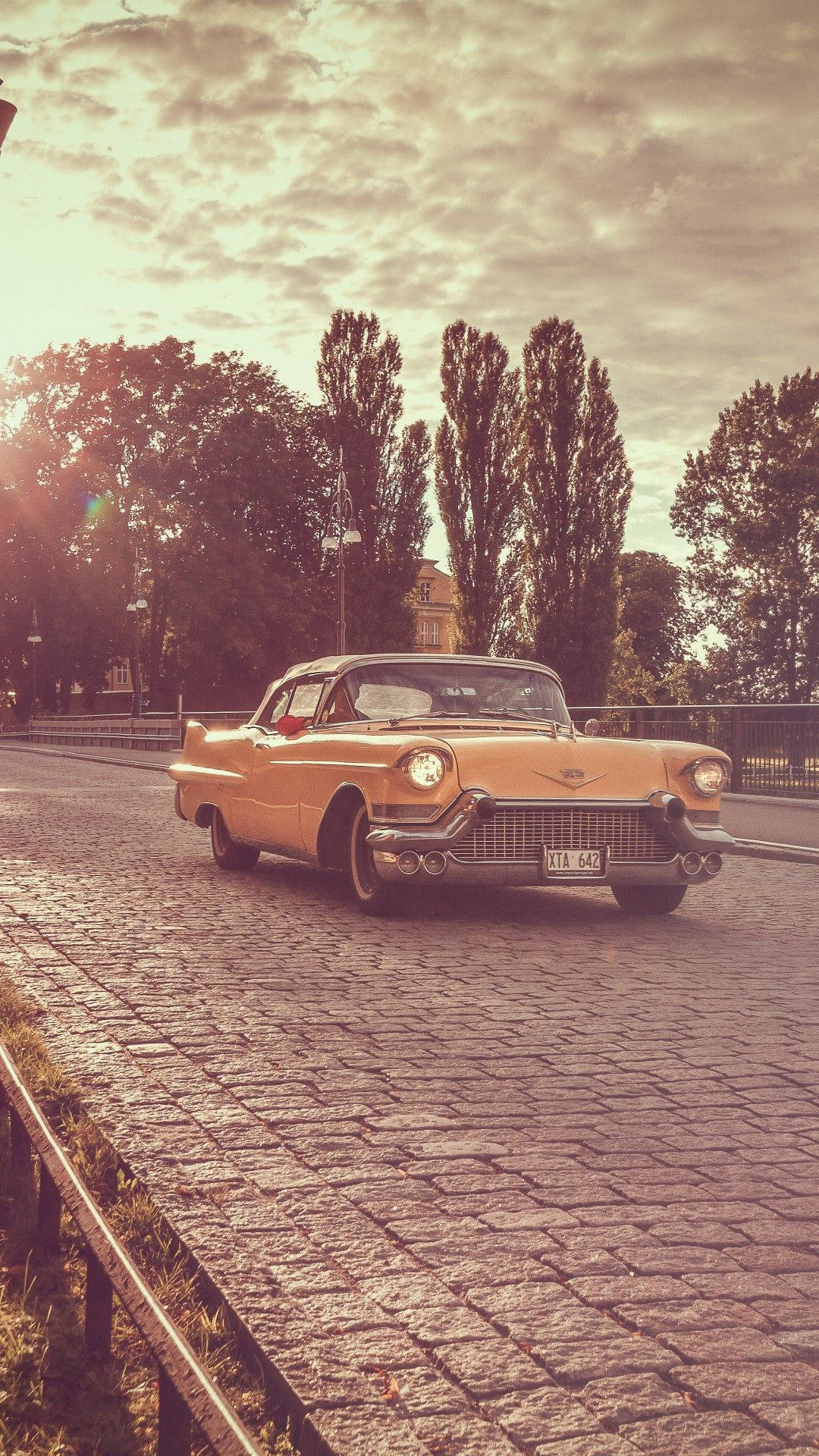 vintage yellow Cadillac, cobblestone road, warm golden sunset sky, Full HD Phone Wallpaper