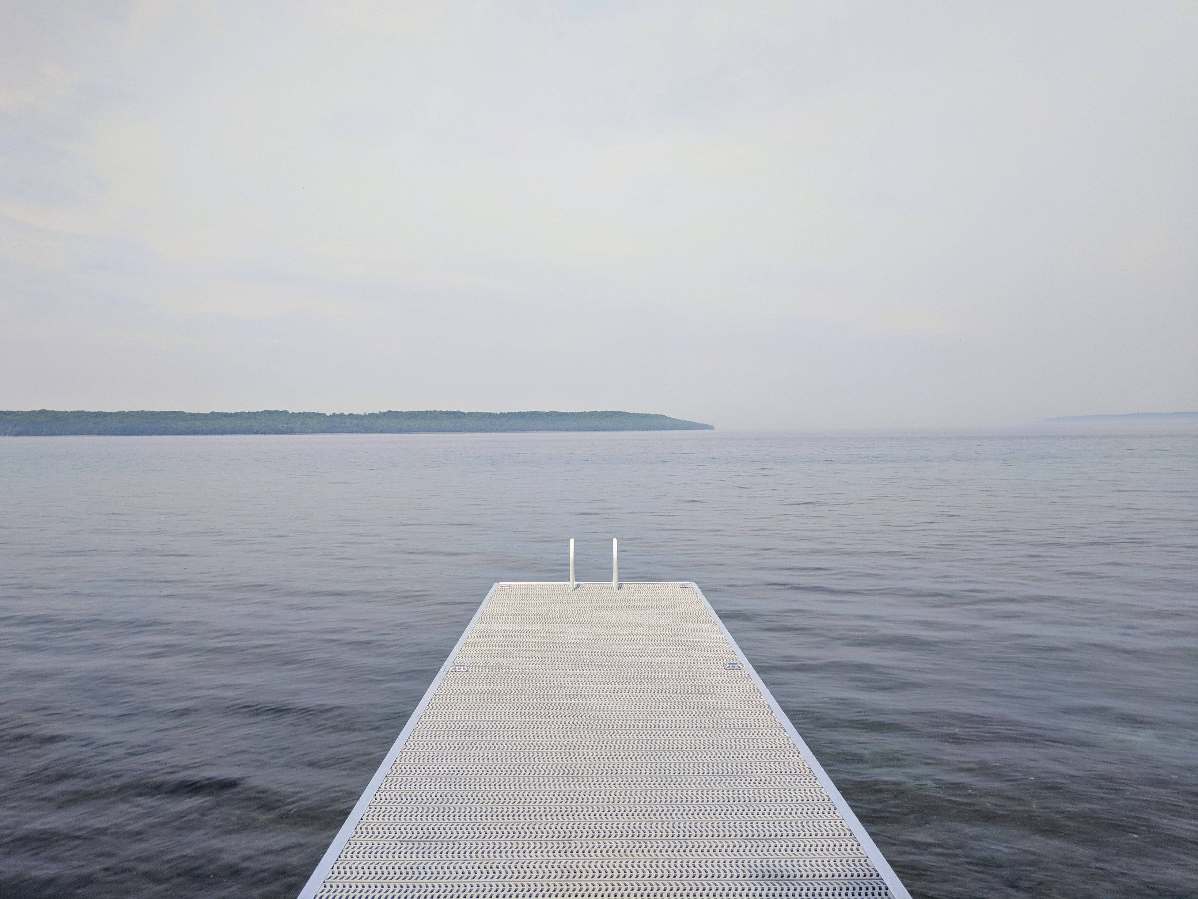 white metal dock, calm gray water, tree-lined shore, 4K Desktop Wallpaper