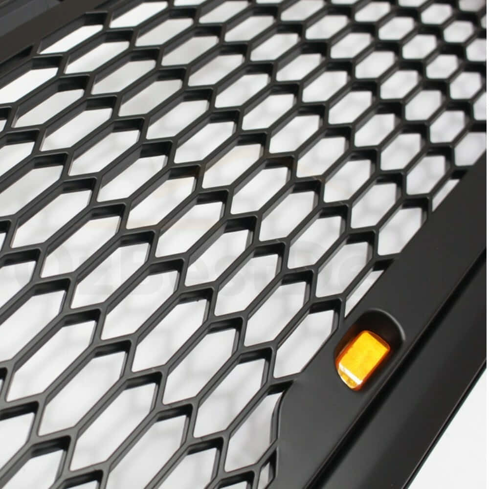 black hexagonal mesh grille, glowing amber indicator light, close-up, SD Desktop Wallpaper