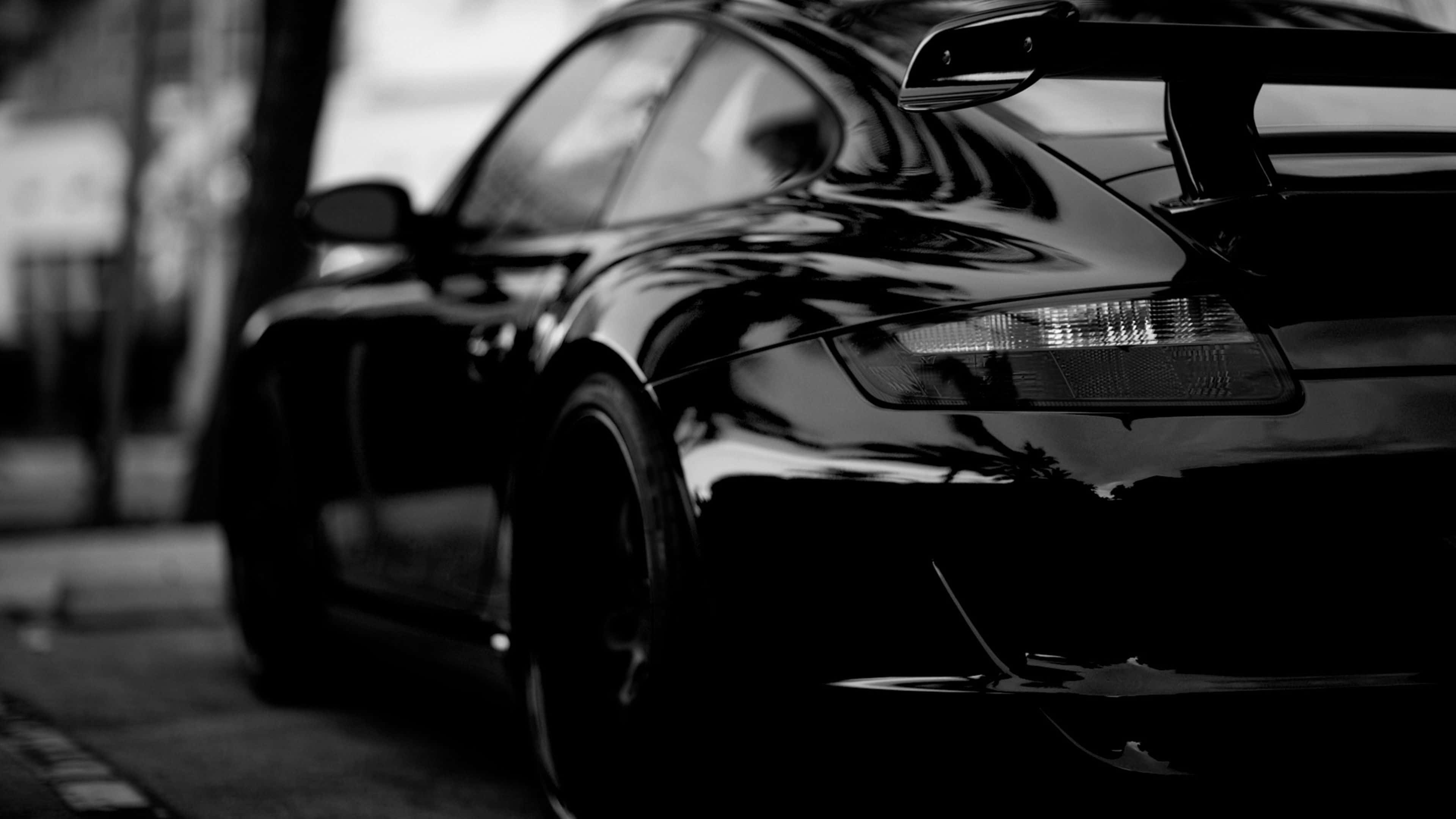 sleek black sports car, rear spoiler, city street, 4K Desktop Wallpaper