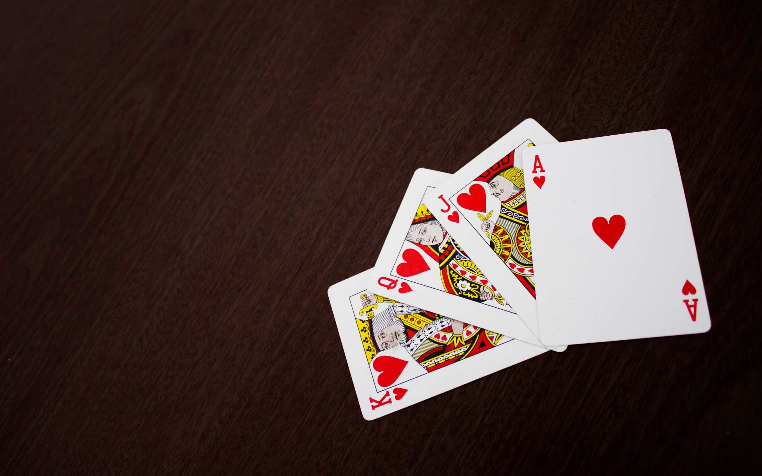 heart playing cards, dark wooden surface, rich grain texture, 2K Desktop Wallpaper