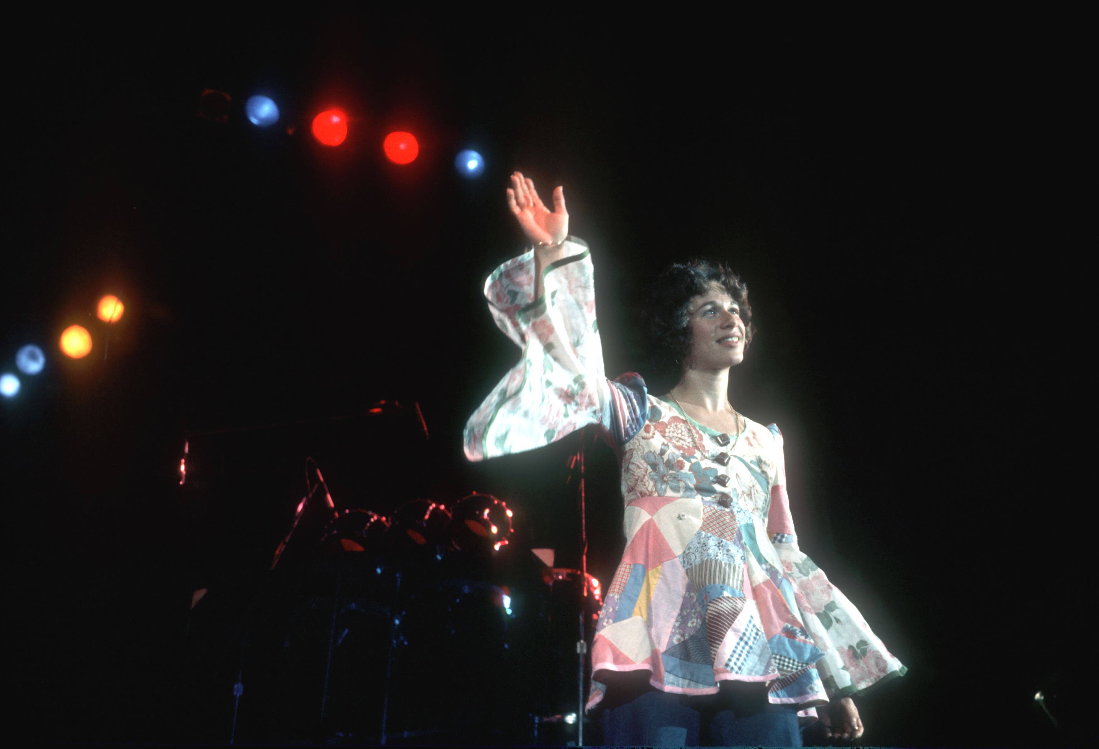 Carole King, colorful patchwork dress, vibrant stage lights, 2K Desktop Wallpaper