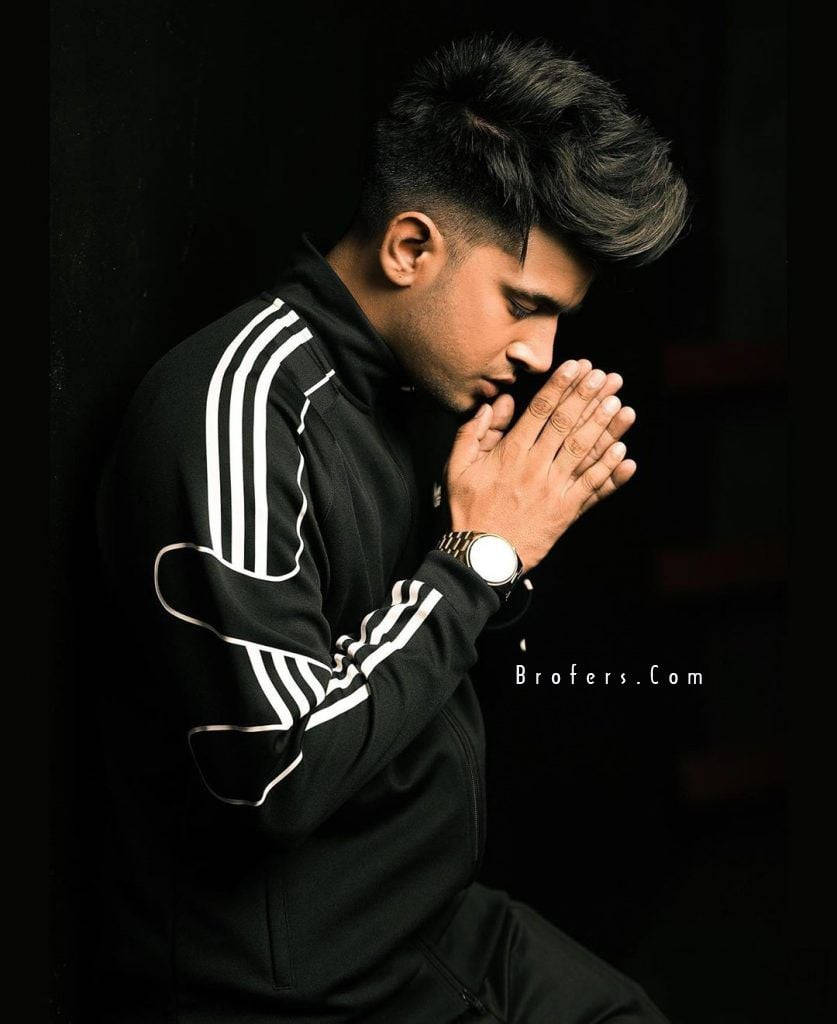 Carryminati, black Adidas tracksuit, kneels with hands clasped in prayer, SD Phone Wallpaper
