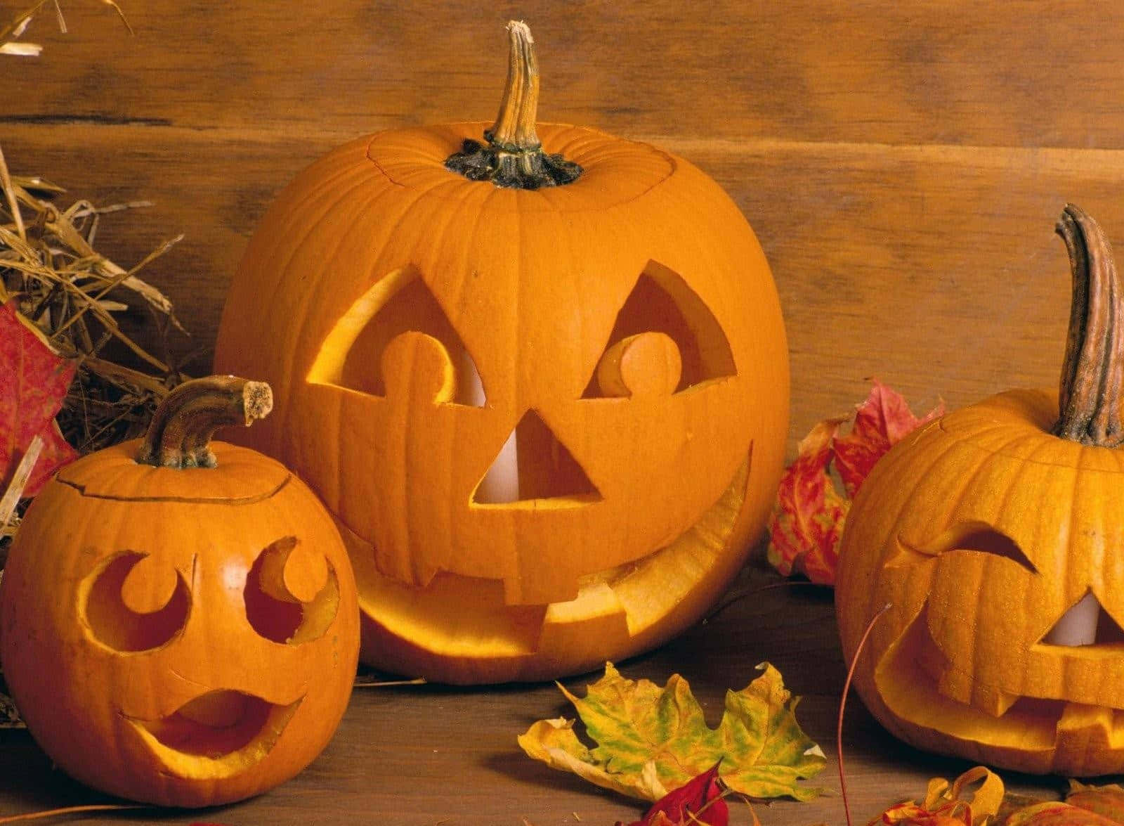 carved jack-o'-lanterns, glowing faces, wooden table, HD Desktop Wallpaper