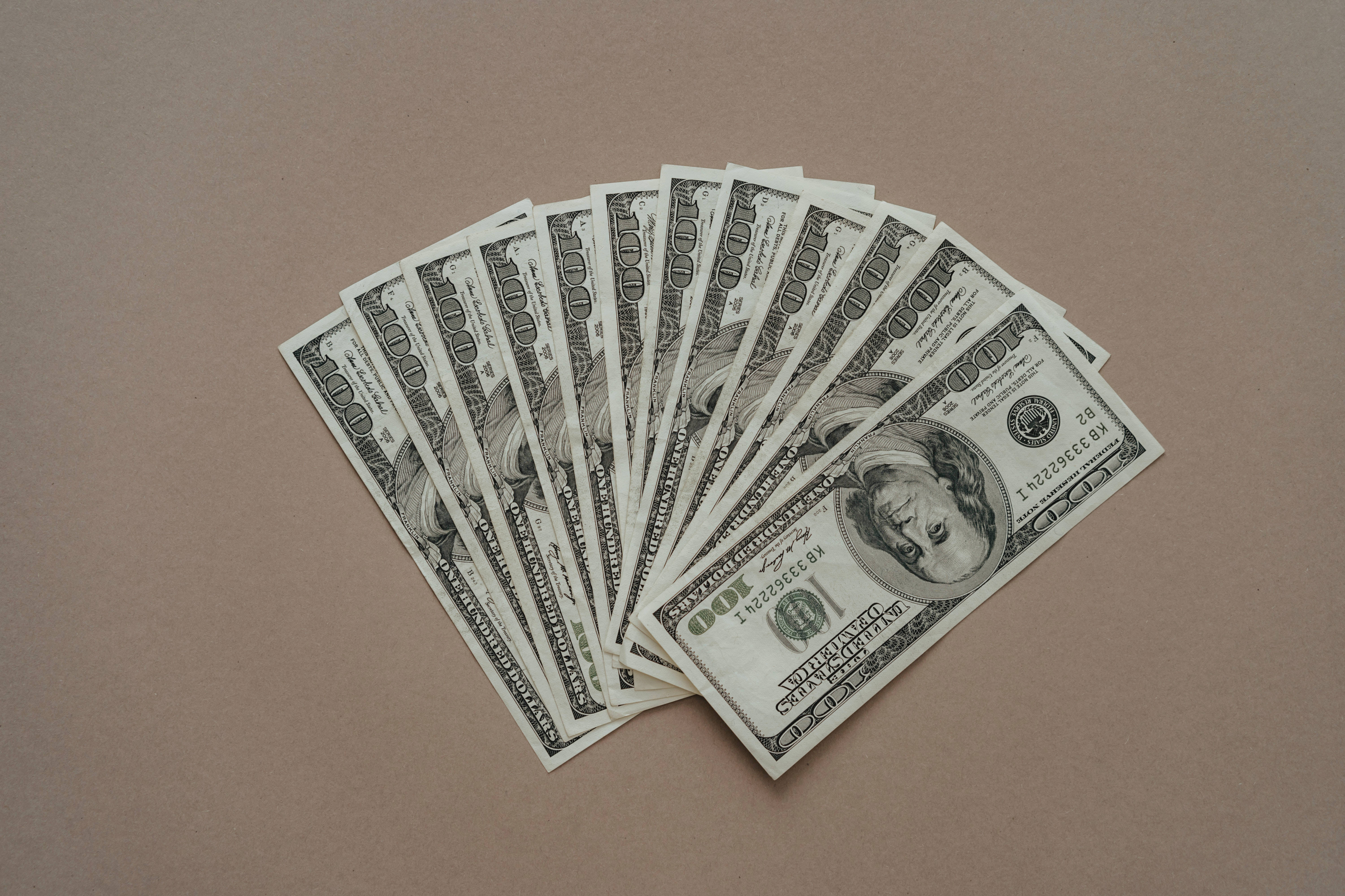 one hundred dollar bills, muted brown surface, 5K Desktop Wallpaper
