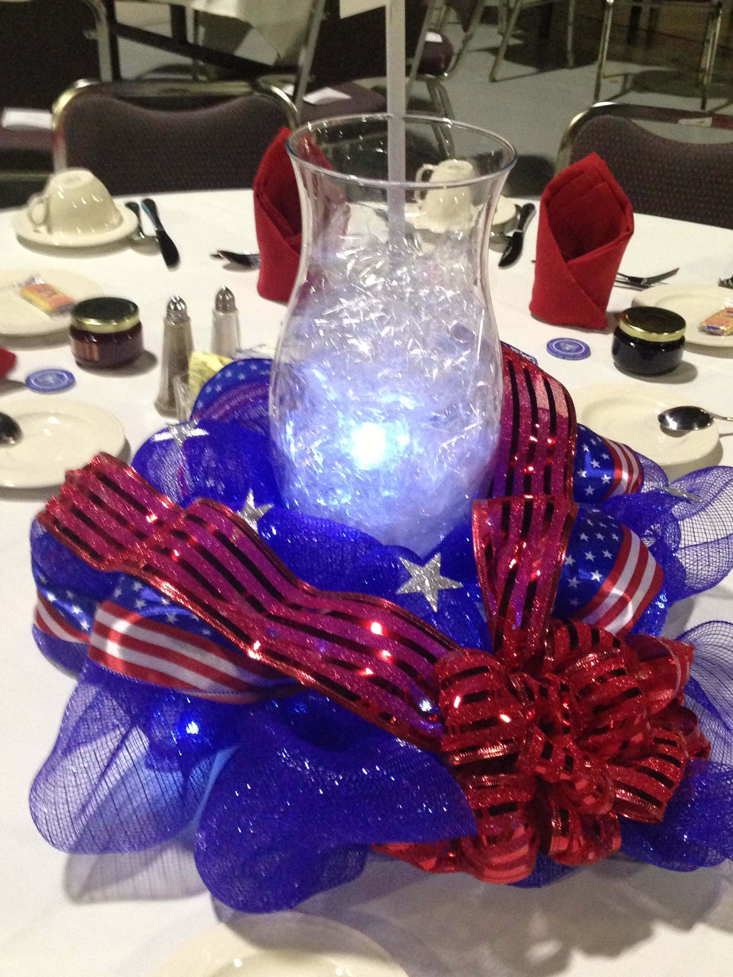 patriotic table centerpiece, blue red and white mesh ribbon stars, glowing glass vase, 2K Phone Wallpaper