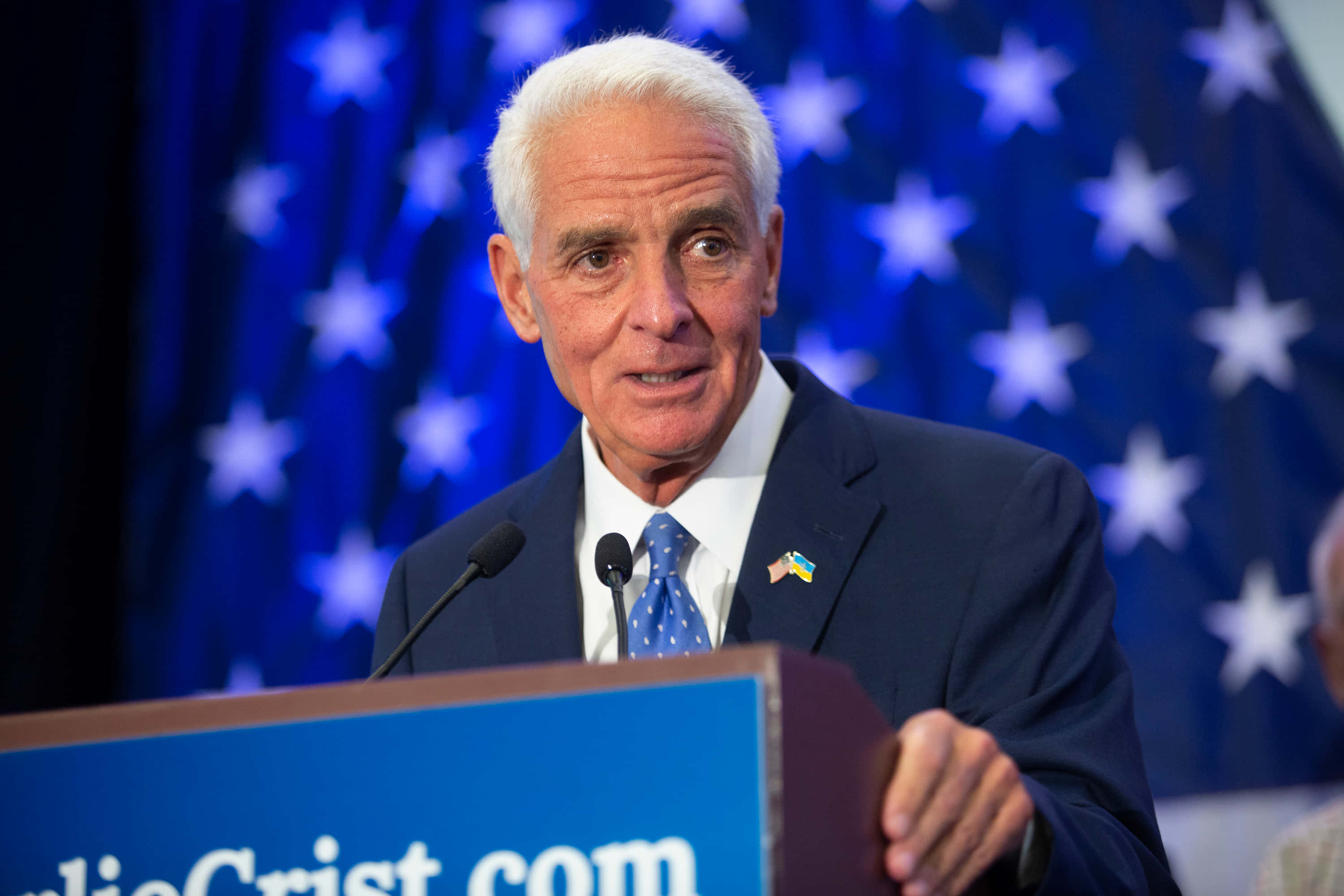 Charlie Crist, podium, blue starry backdrop, 2K Desktop Wallpaper