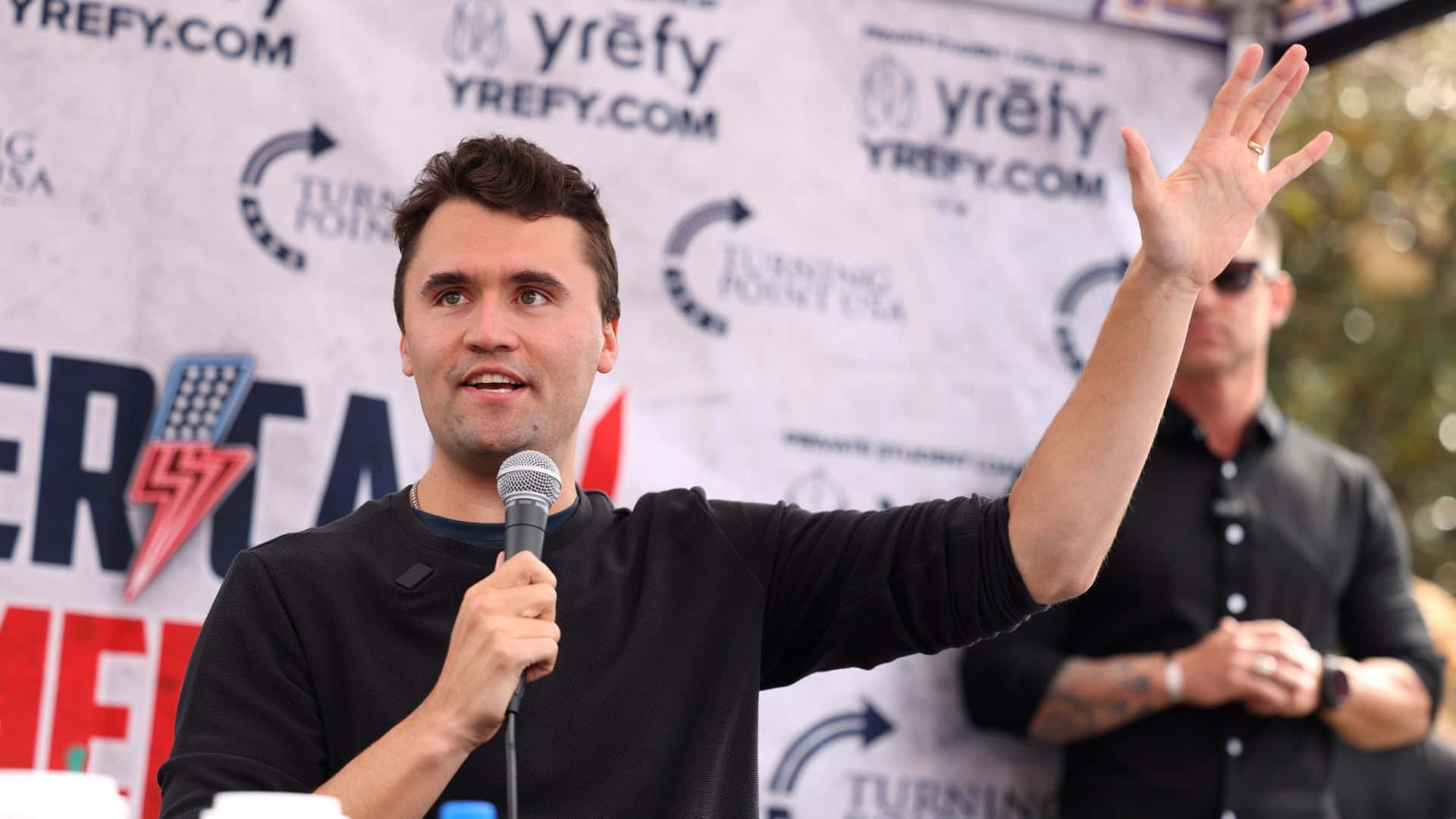 Charlie Kirk, black shirt, microphone, Full HD Desktop Wallpaper