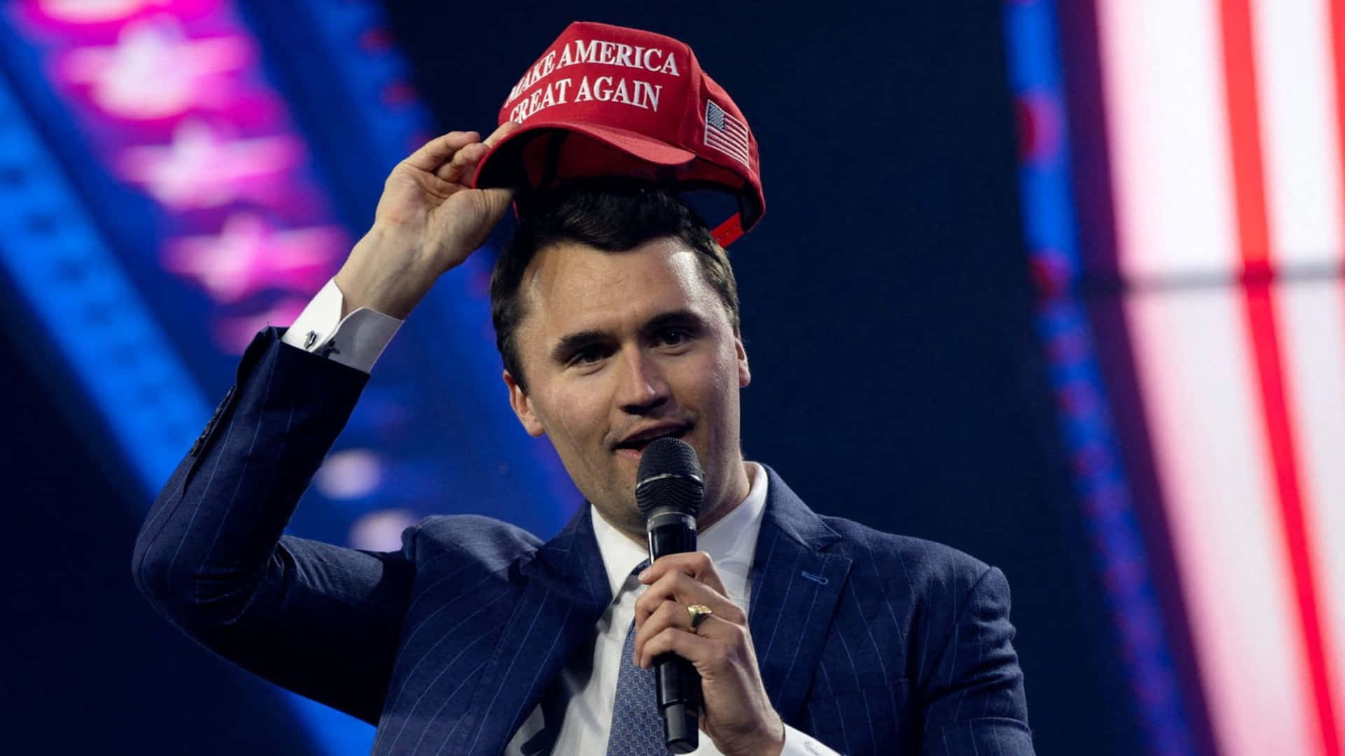 Charlie Kirk, blue suit, red 'Make America Great Again' cap, Full HD Desktop Wallpaper