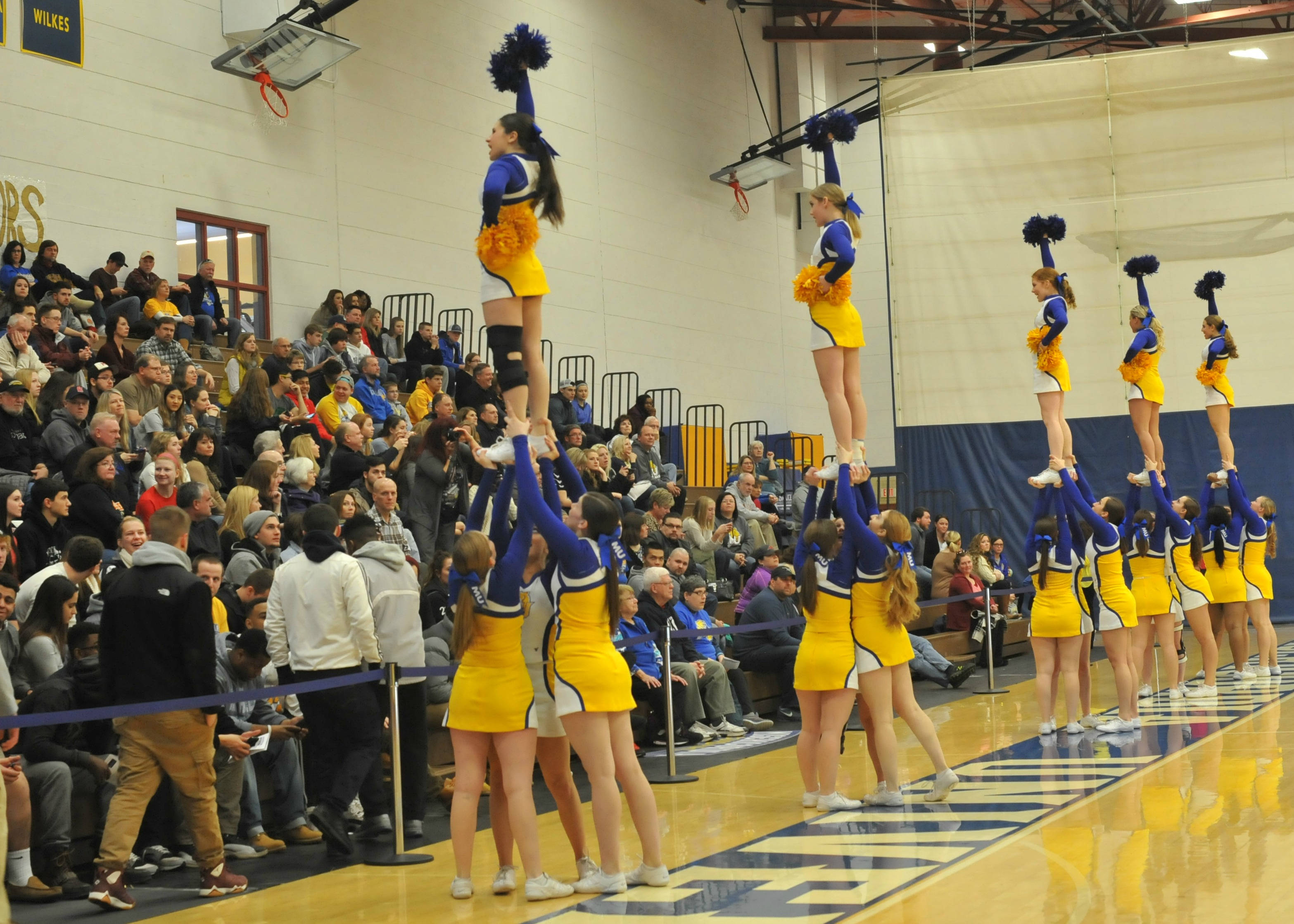 blue and yellow uniforms, synchronized pyramid routine, gymnasium floor, 2K Desktop Wallpaper