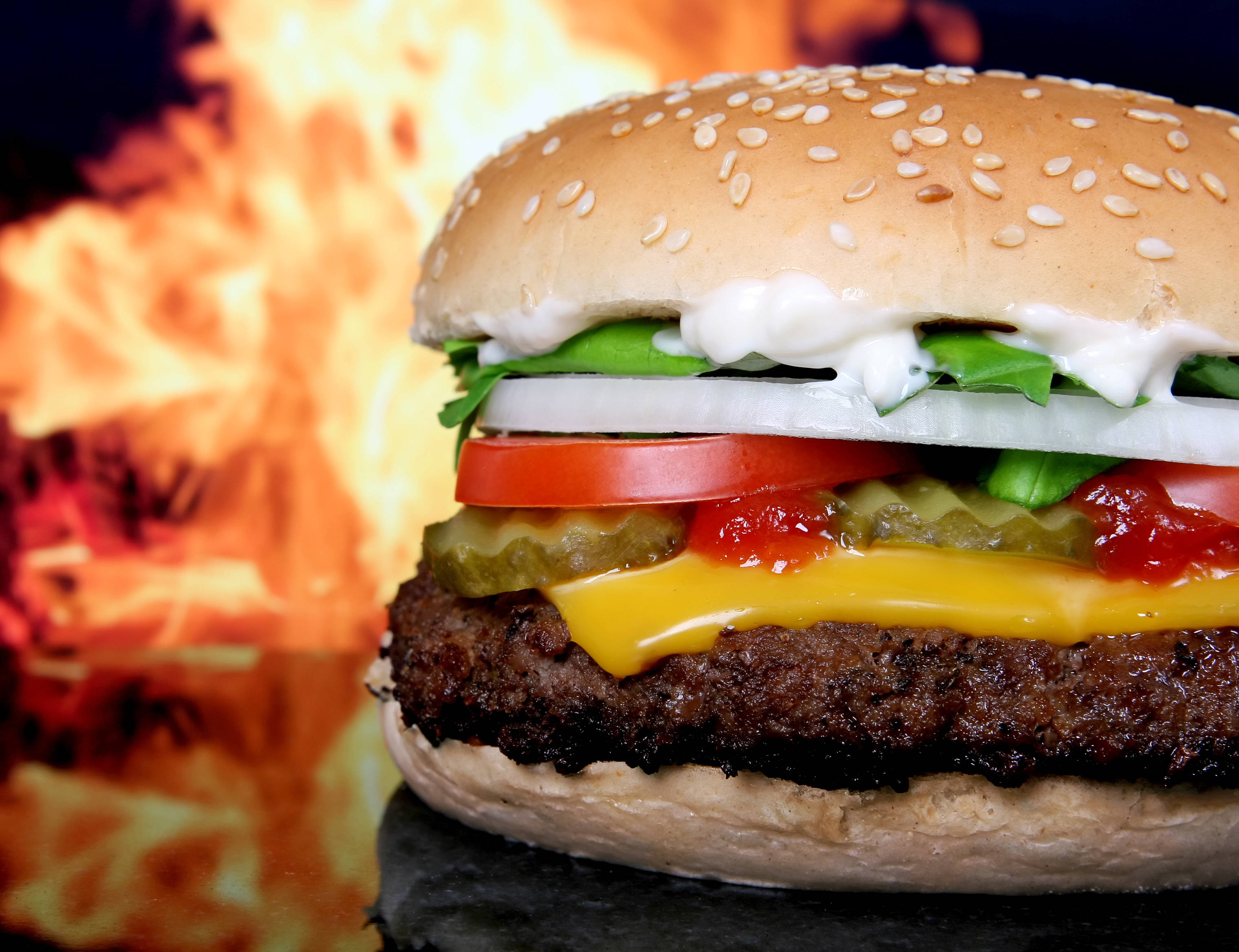 cheeseburger, sesame bun, roaring fire background, 2K Desktop Wallpaper