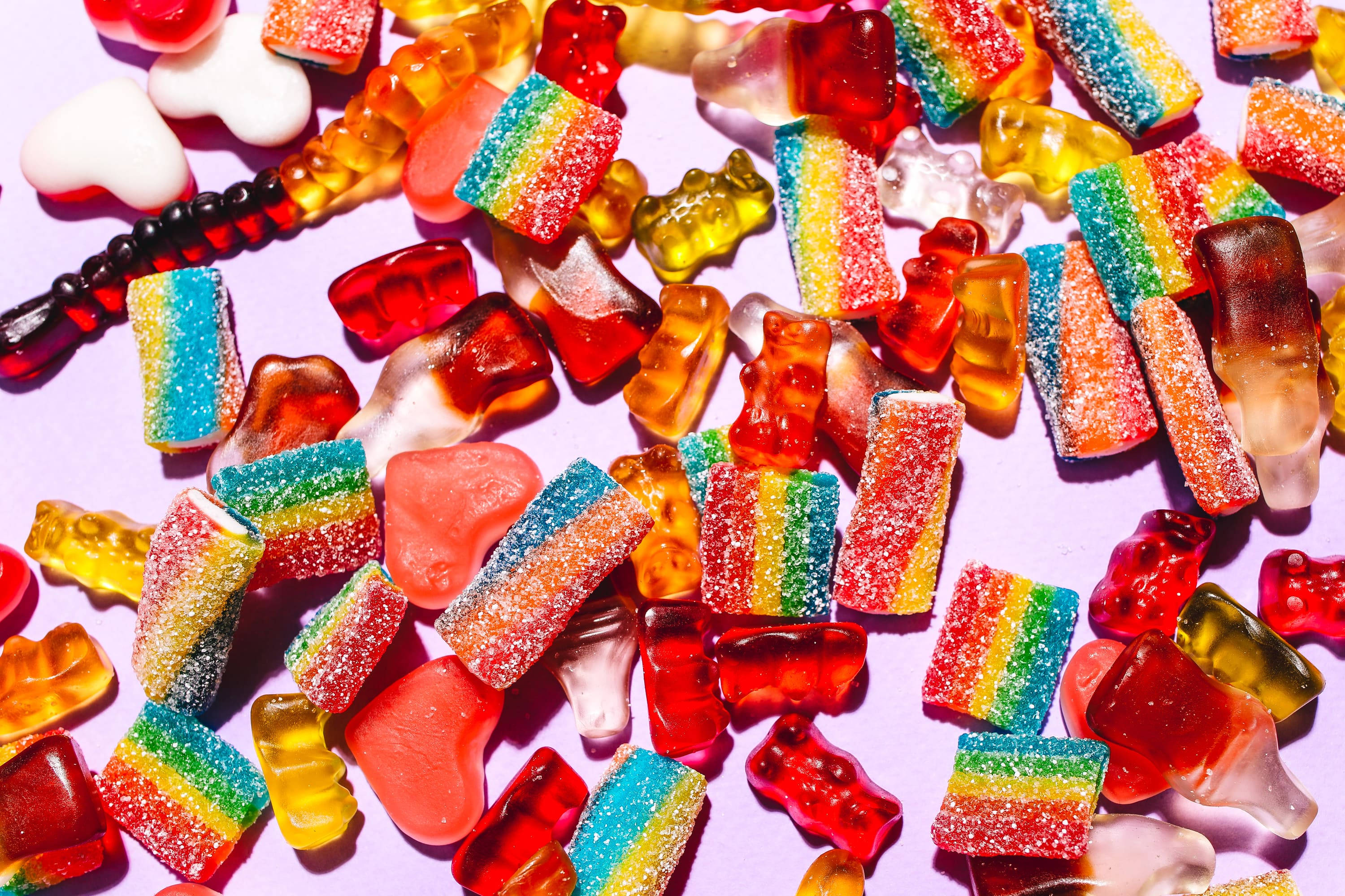 vibrant, rainbow gummy candies, soft purple background, 2K Desktop Wallpaper