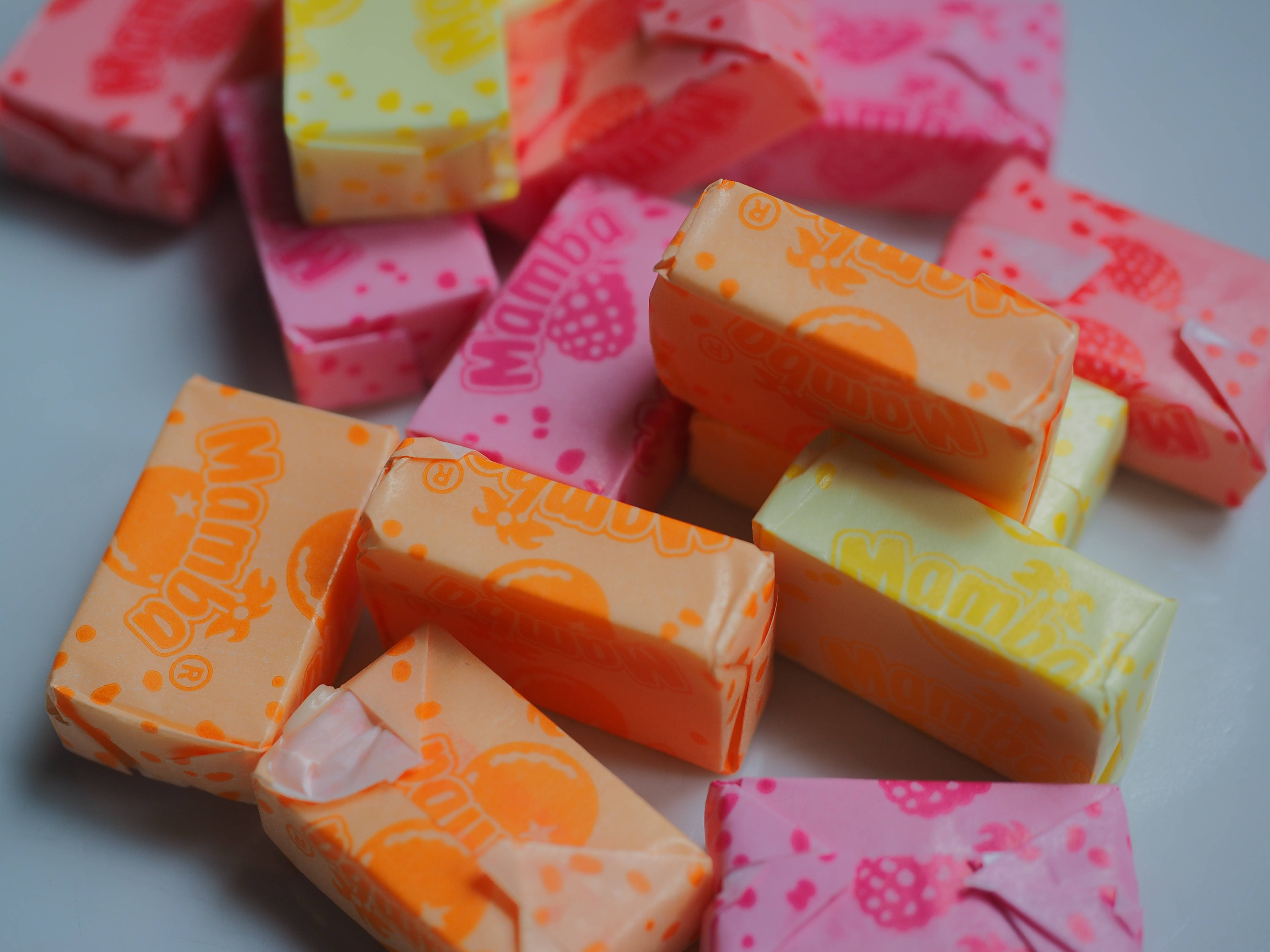 Mamba candy bars, pink yellow and orange wrappers, light gray surface, 4K Desktop Wallpaper