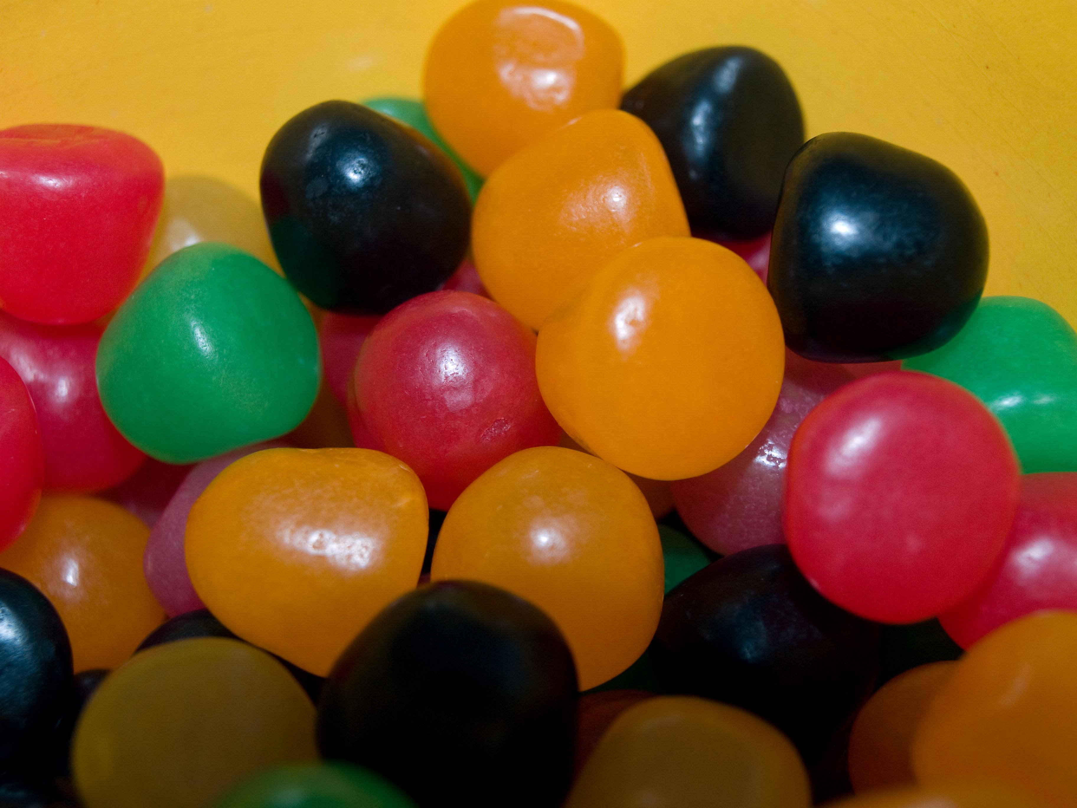 chewy jelly beans, glossy multicolored jelly beans, warm yellow background, 2K Desktop Wallpaper