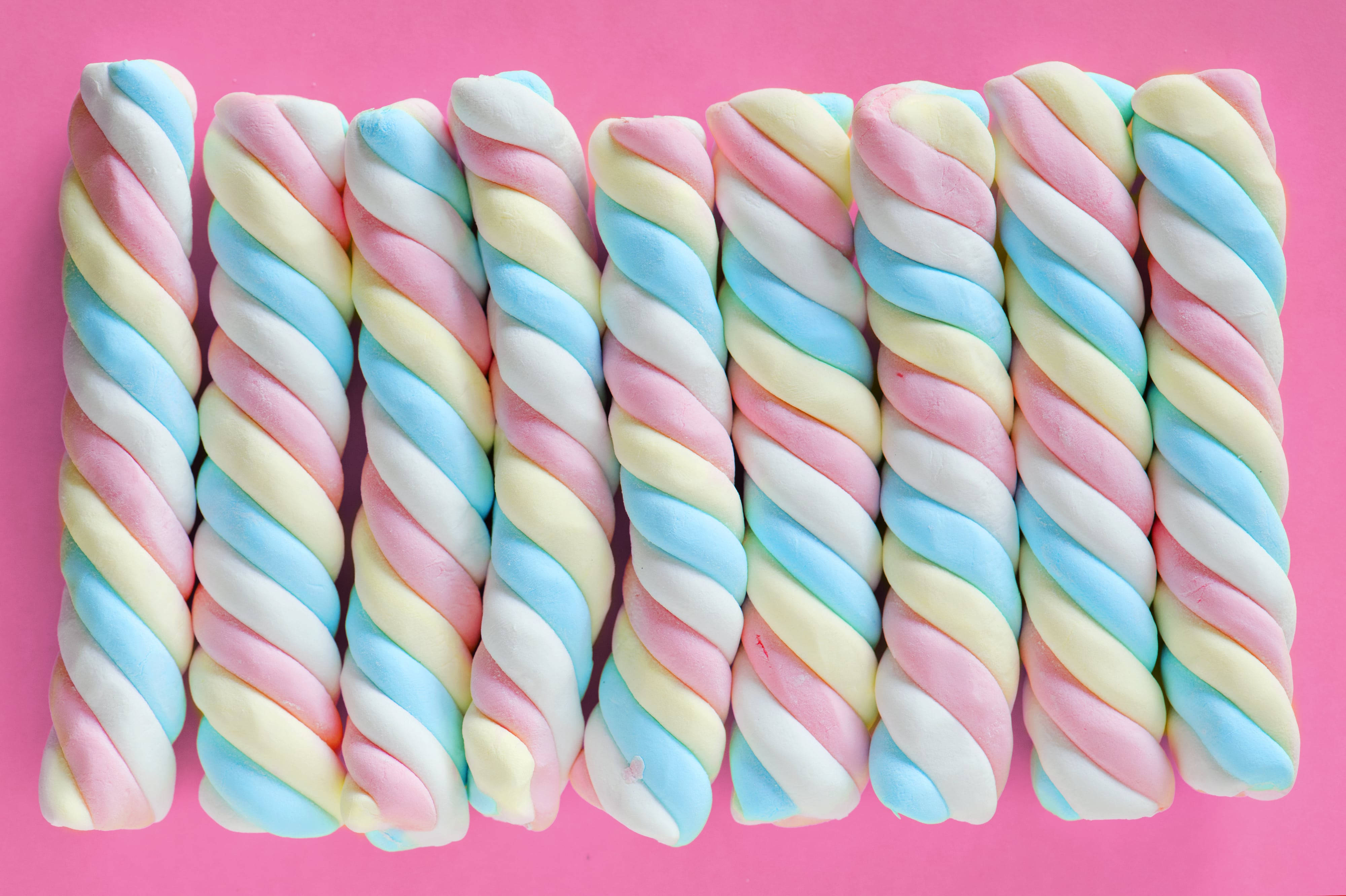 Chewy, pastel rainbow twisted marshmallows, vibrant pink background, 4K Desktop Wallpaper