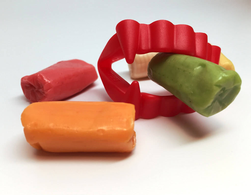 weird chewy candies, red vampire fang-shaped mold, vibrant red orange green and beige, SD Desktop Wallpaper