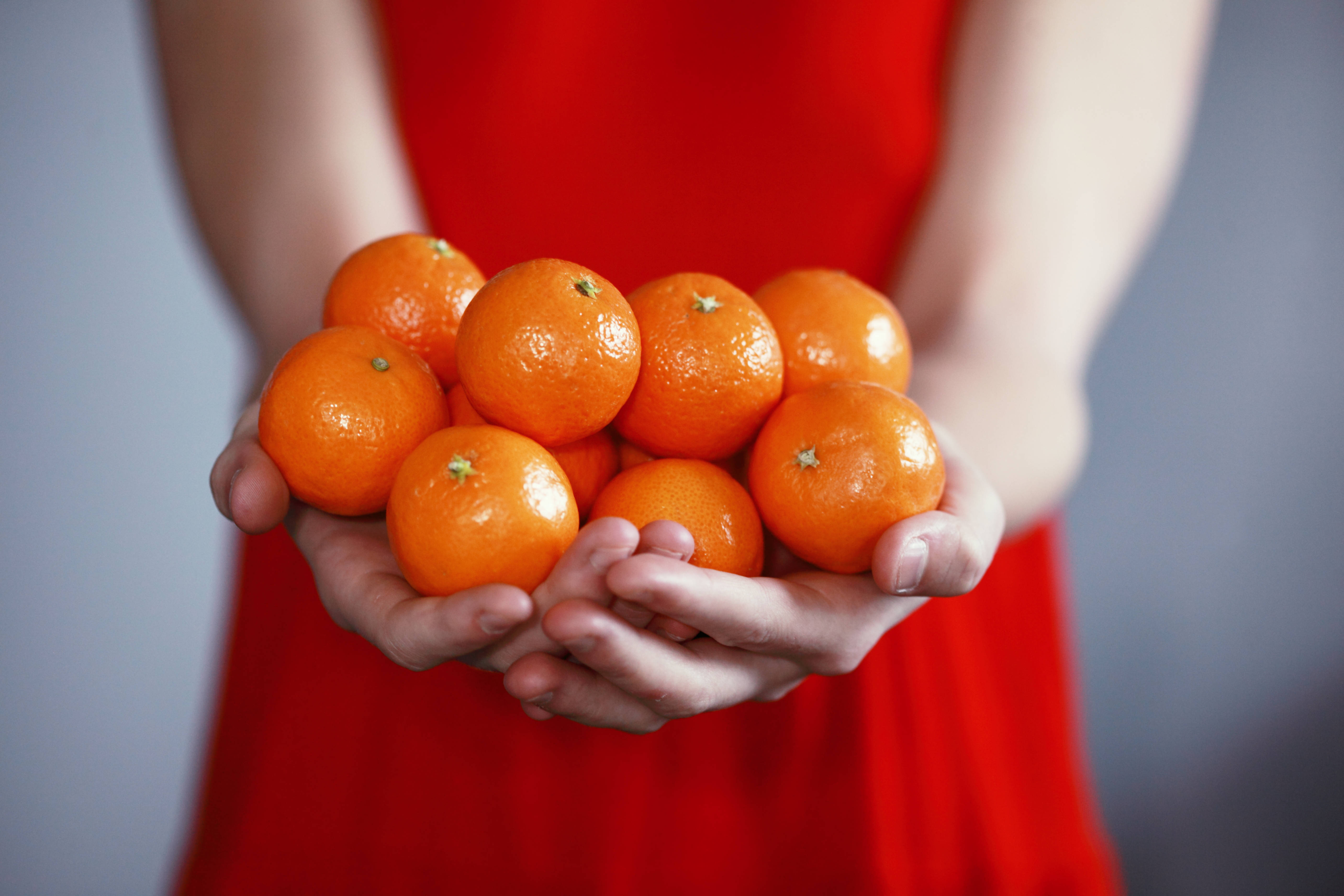 red dress, vibrant cluster of fresh tangerines, soft gray background, 5K Desktop Wallpaper