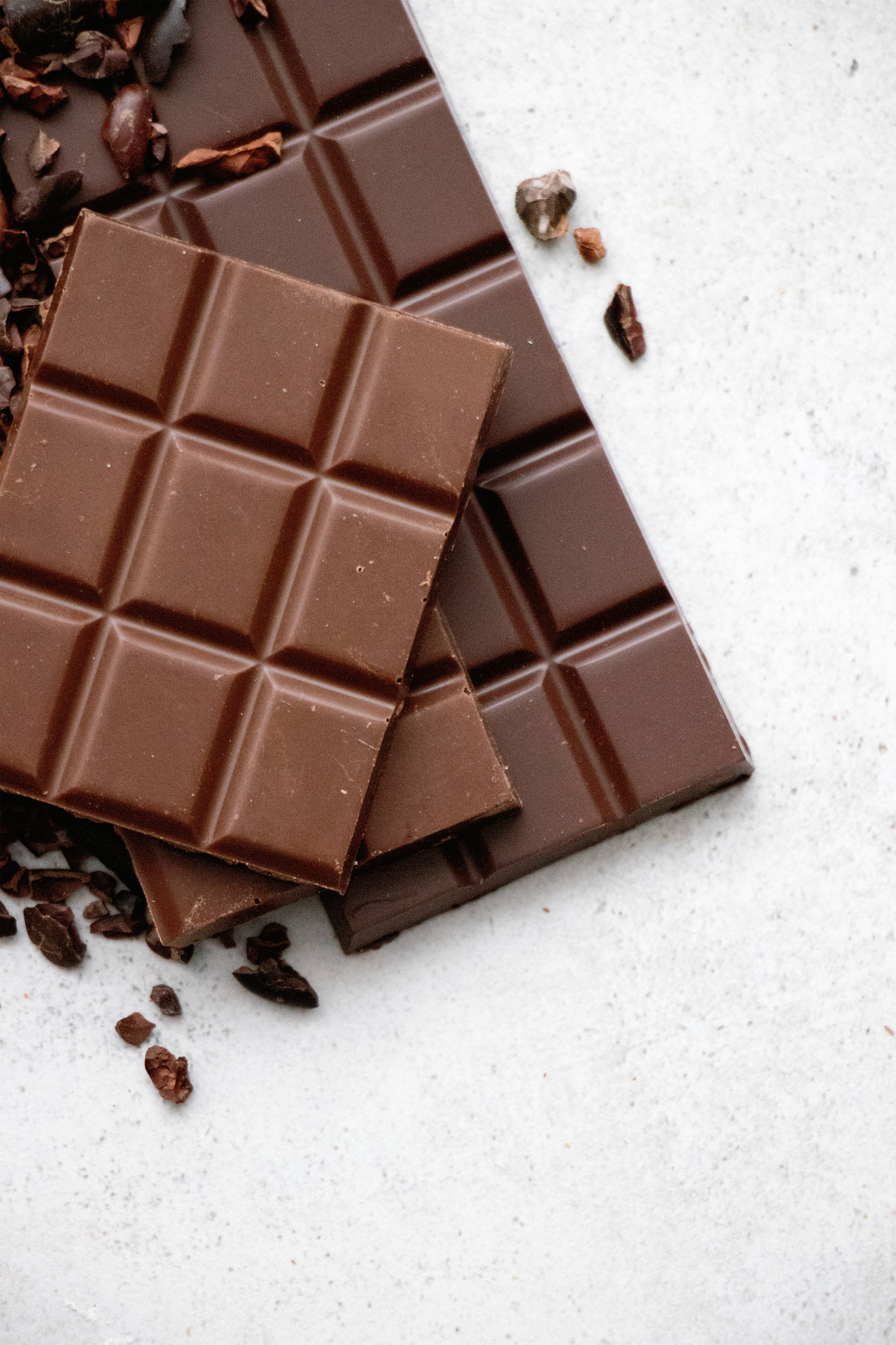 dark chocolate bars, cocoa nibs, white textured surface, 4K Phone Wallpaper