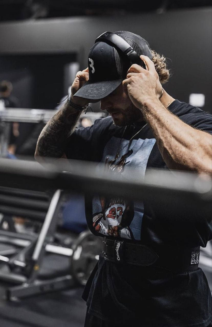 Chris Bumstead, headphones, dimly lit gym, SD Phone Wallpaper