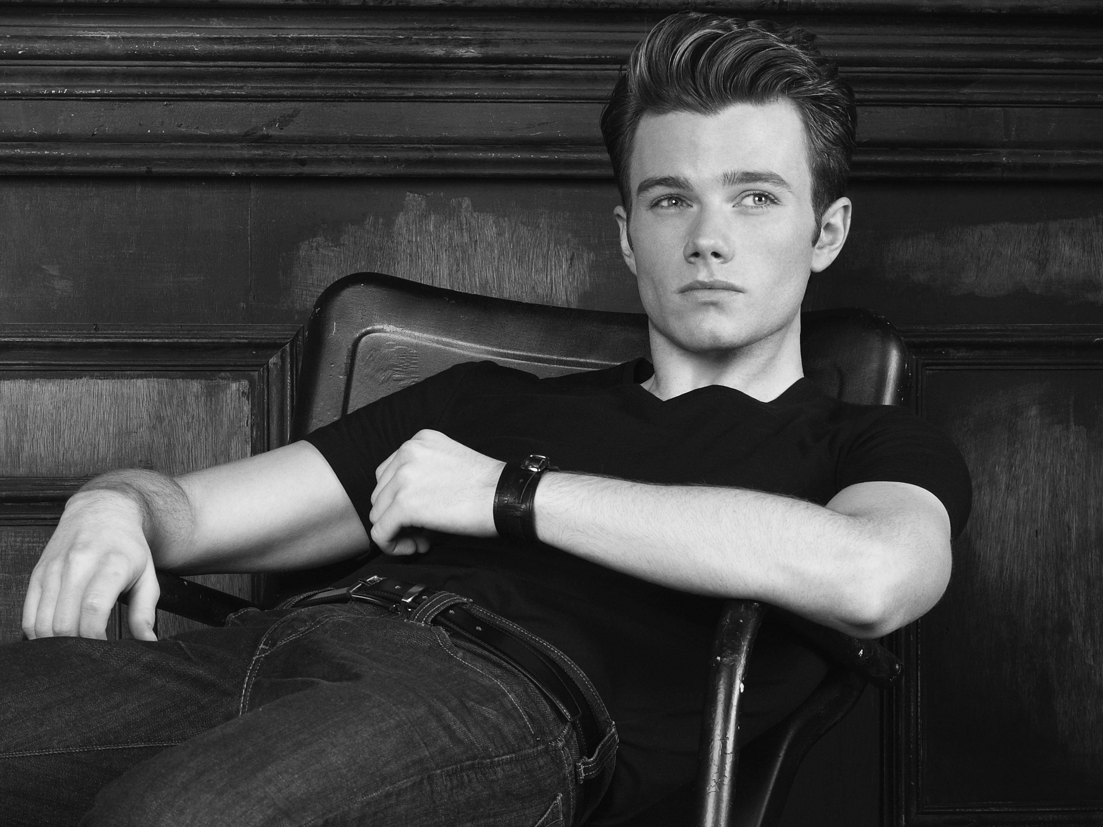 Chris Colfer, leather chair, dark wood-paneled wall, 2K Desktop Wallpaper