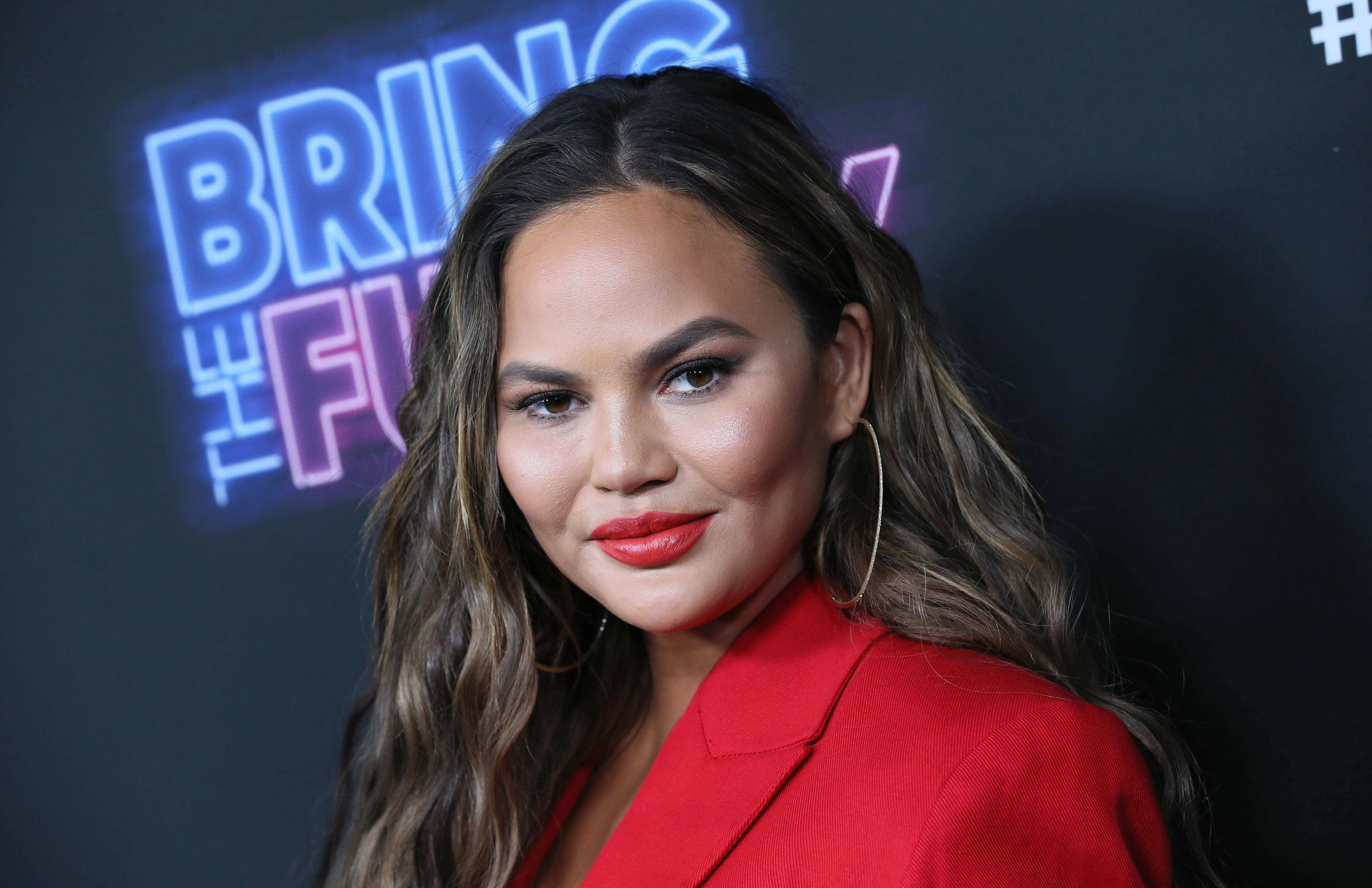 Chrissy Teigen, red blazer, neon 'BRING THE FUNK' backdrop, 4K Desktop Wallpaper