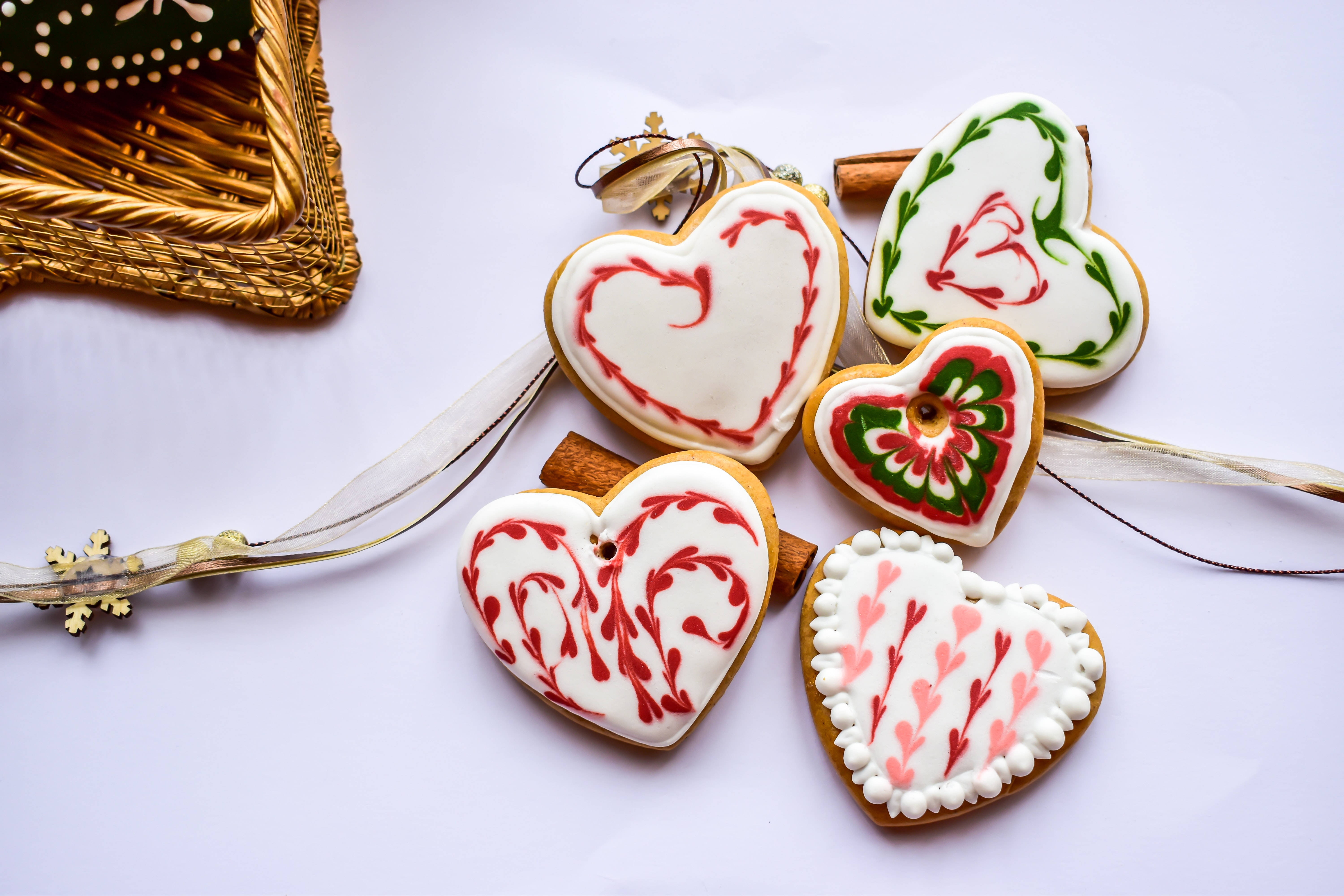 heart-shaped gingerbread cookies, red green and pink icing patterns, white surface, 5K Desktop Wallpaper