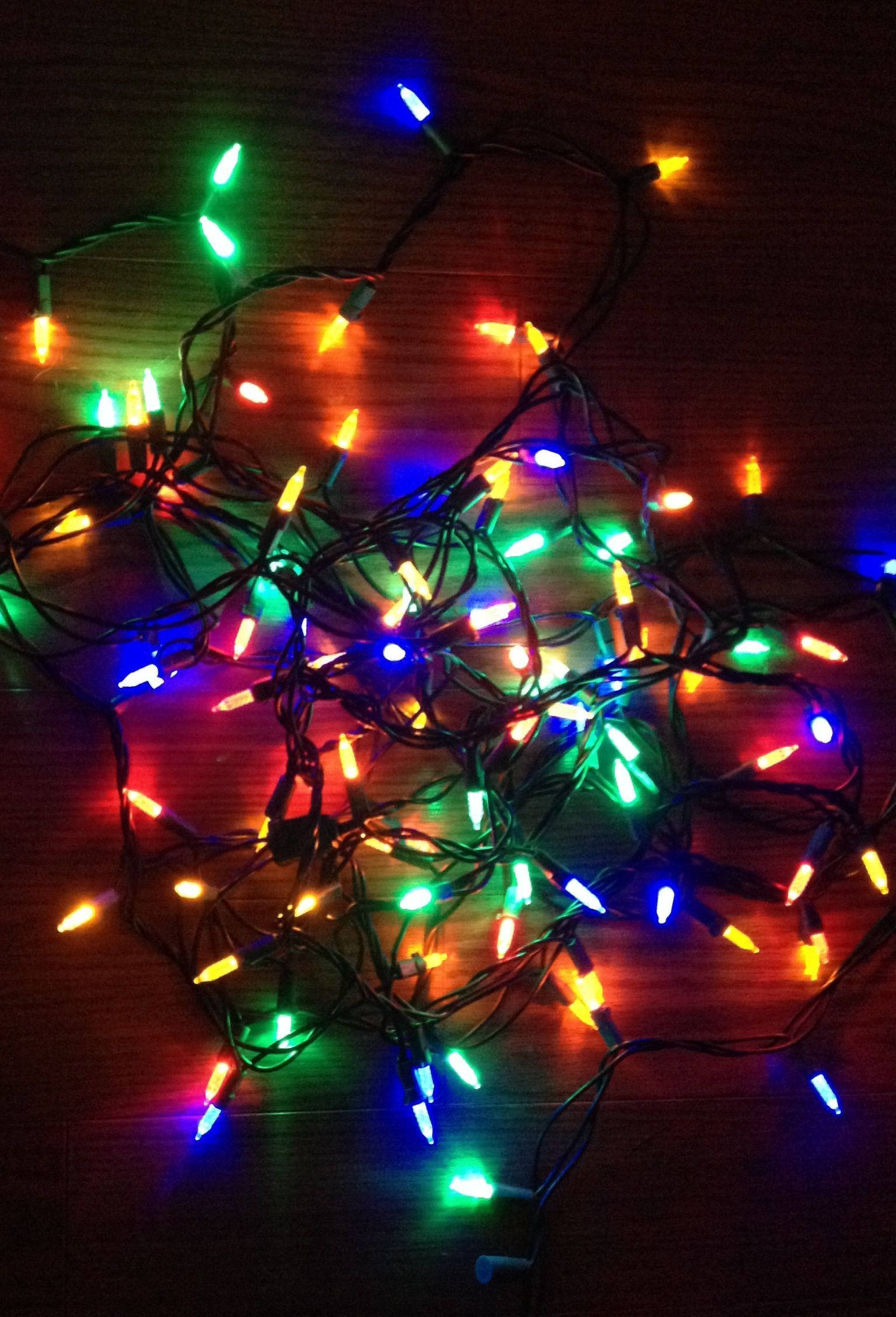 Christmas lights, multicolored fairy lights, dark wooden surface, Full HD Phone Wallpaper