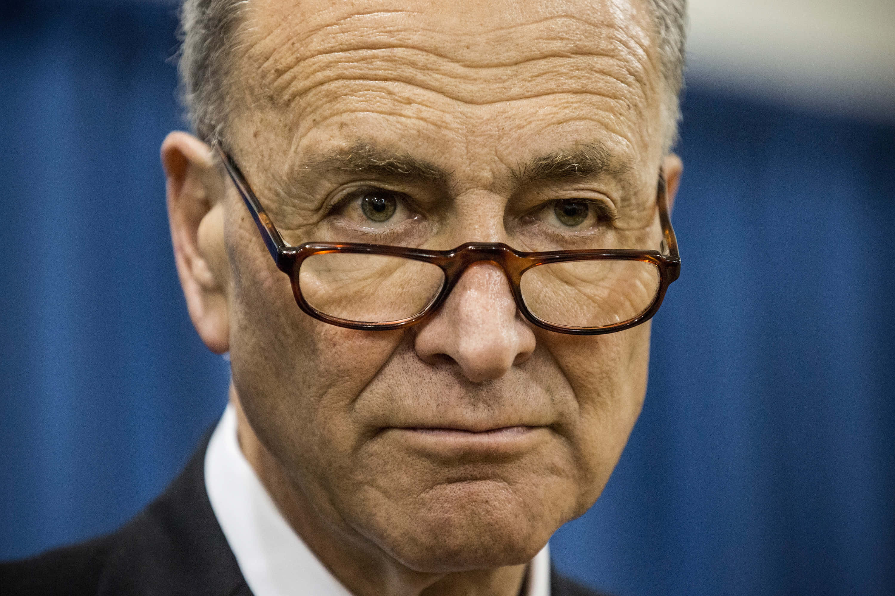 Chuck Schumer, tortoiseshell glasses, blue curtain, 2K Desktop Wallpaper