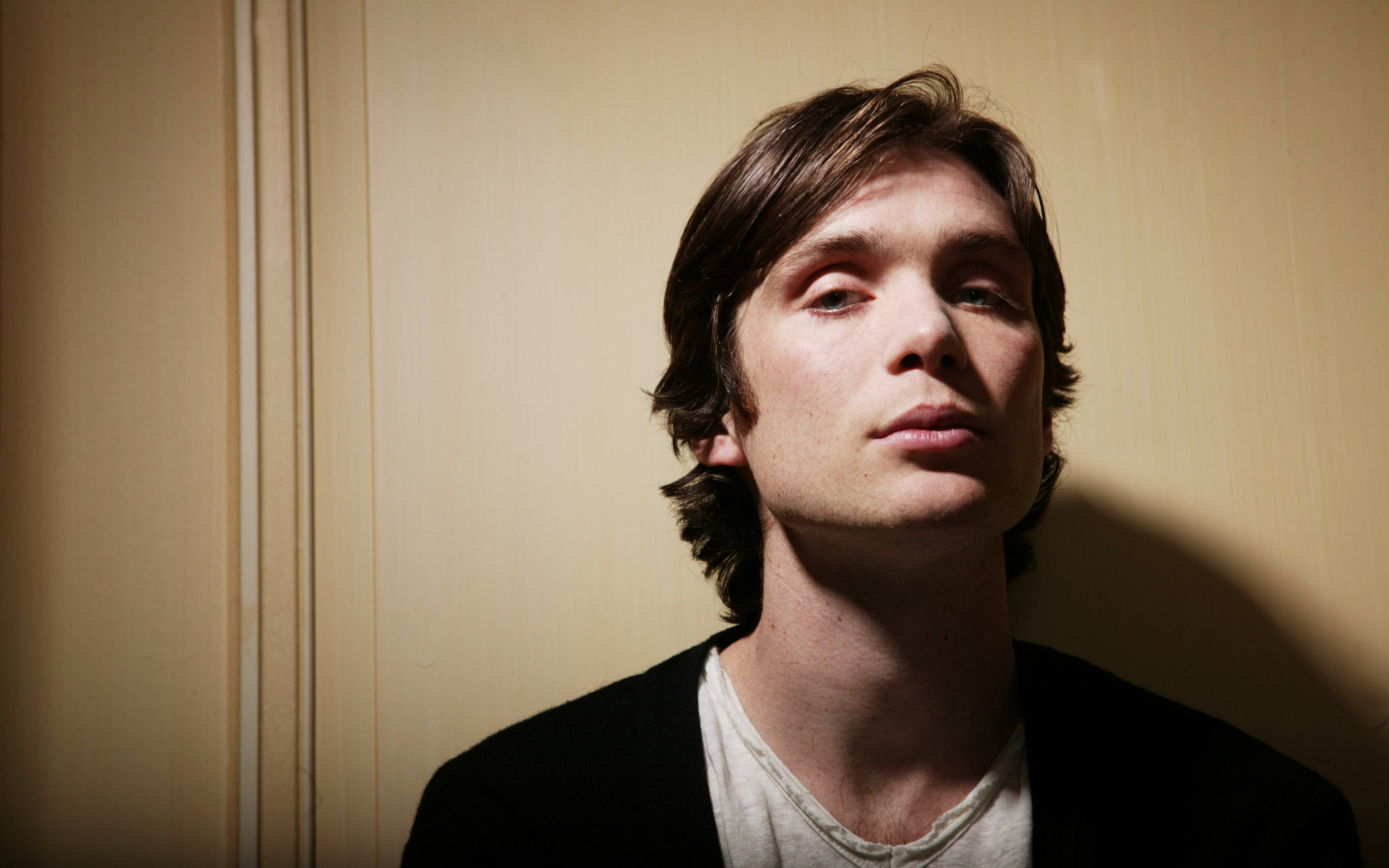 Cillian Murphy, tousled brown hair, warmly lit wooden paneled wall, 4K Desktop Wallpaper