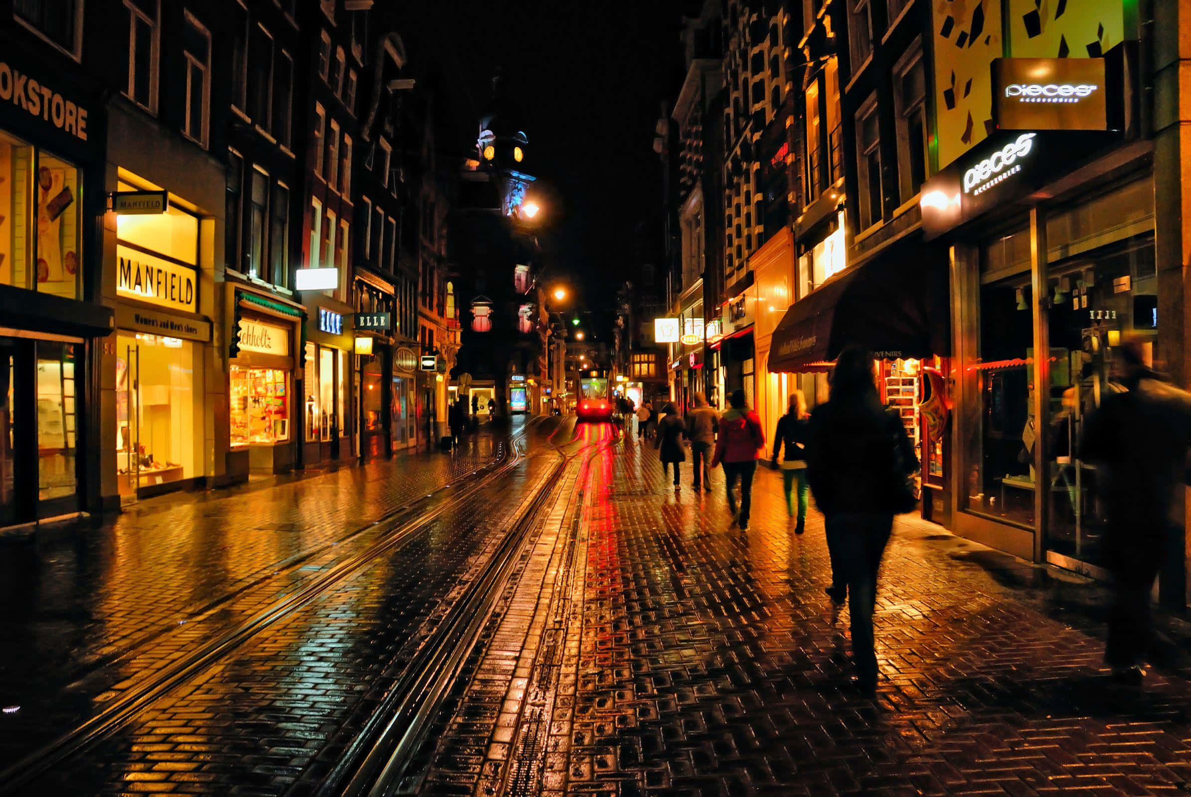 bustling city night street, rain-slicked cobblestone street, glowing shop windows, Full HD Desktop Wallpaper