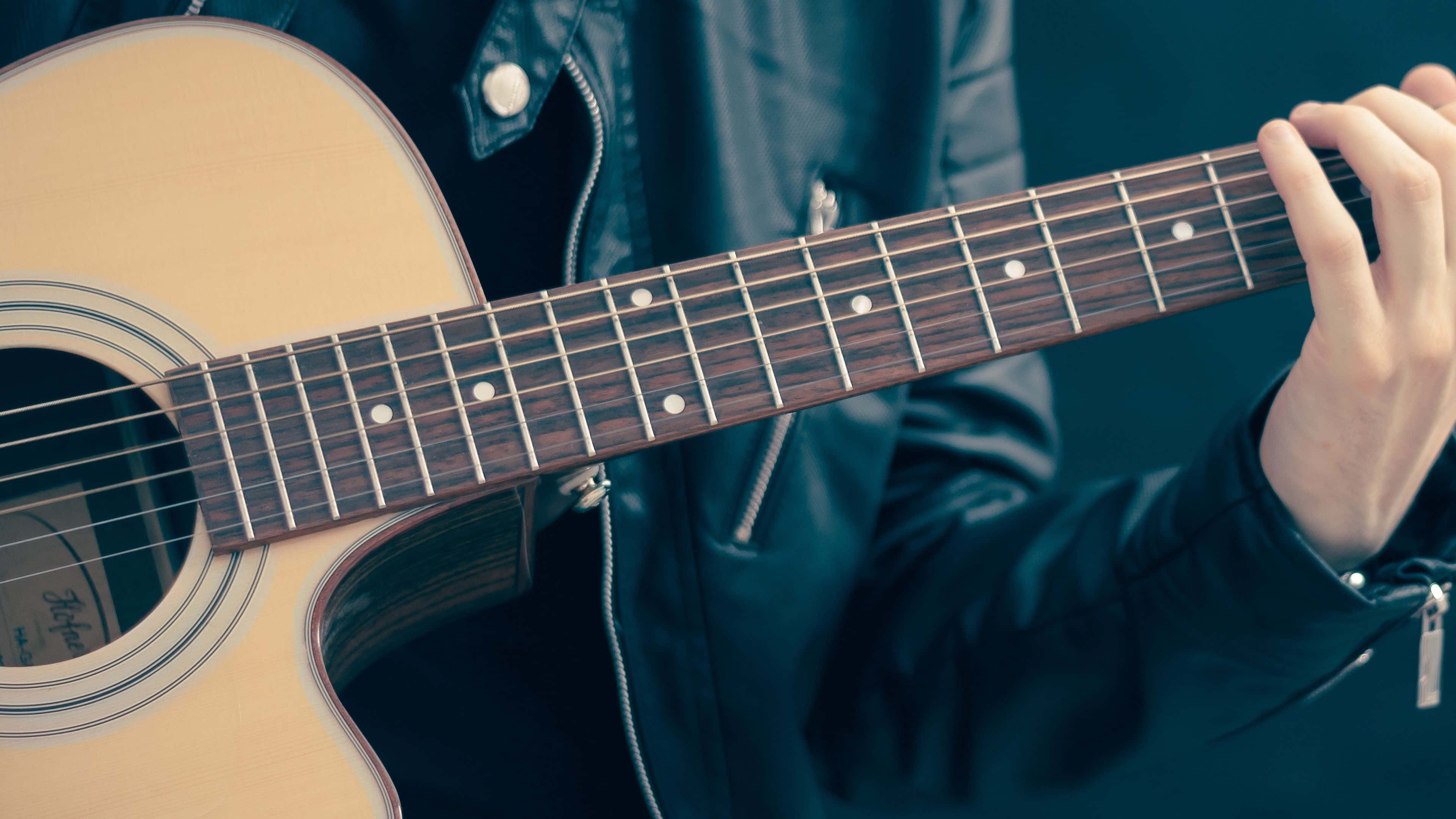 light wood acoustic guitar, dark jacket, close-up, 4K Desktop Wallpaper