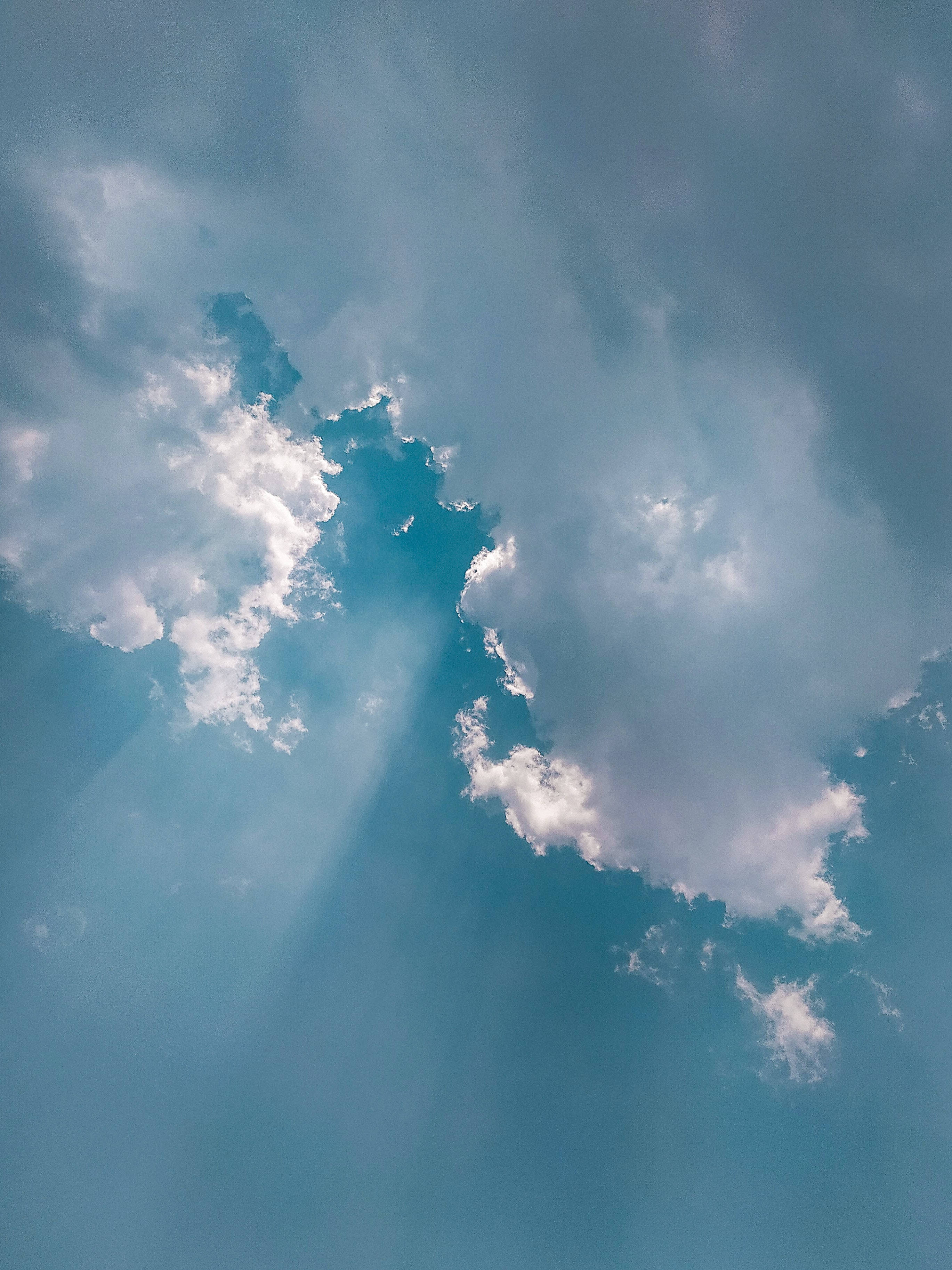 Sunlight beams, fluffy white clouds, serene blue sky, 2K Phone Wallpaper