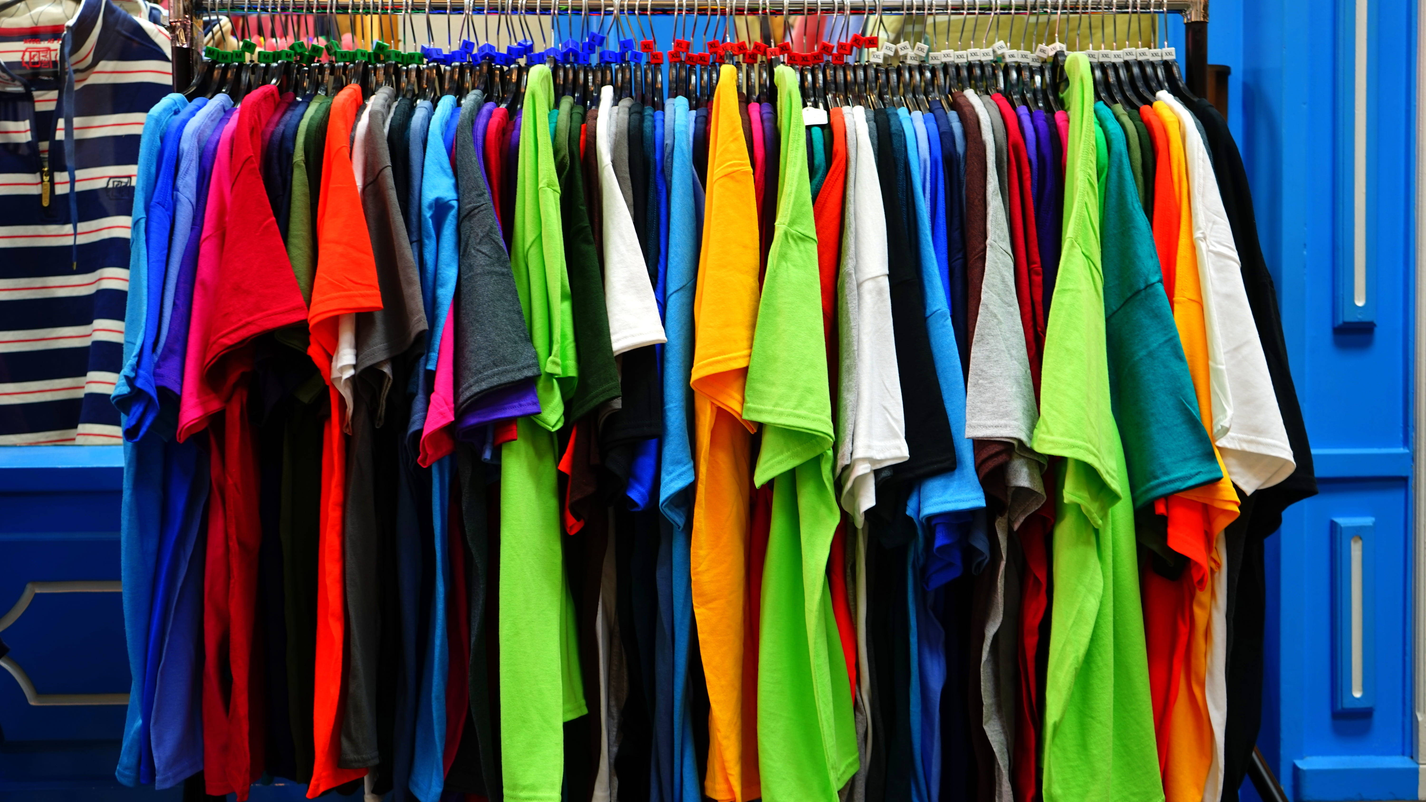 colorful t-shirts, metal rack, bold blue wall, 5K Desktop Wallpaper
