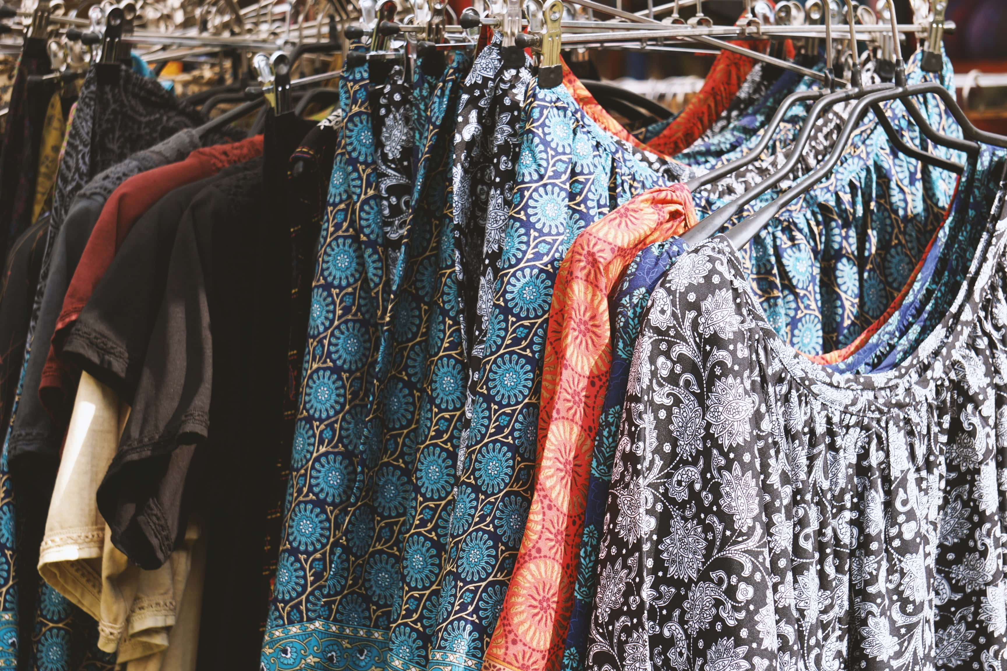boho hippie clothing rack, vibrant patterned dresses, blue orange and black, 2K Desktop Wallpaper
