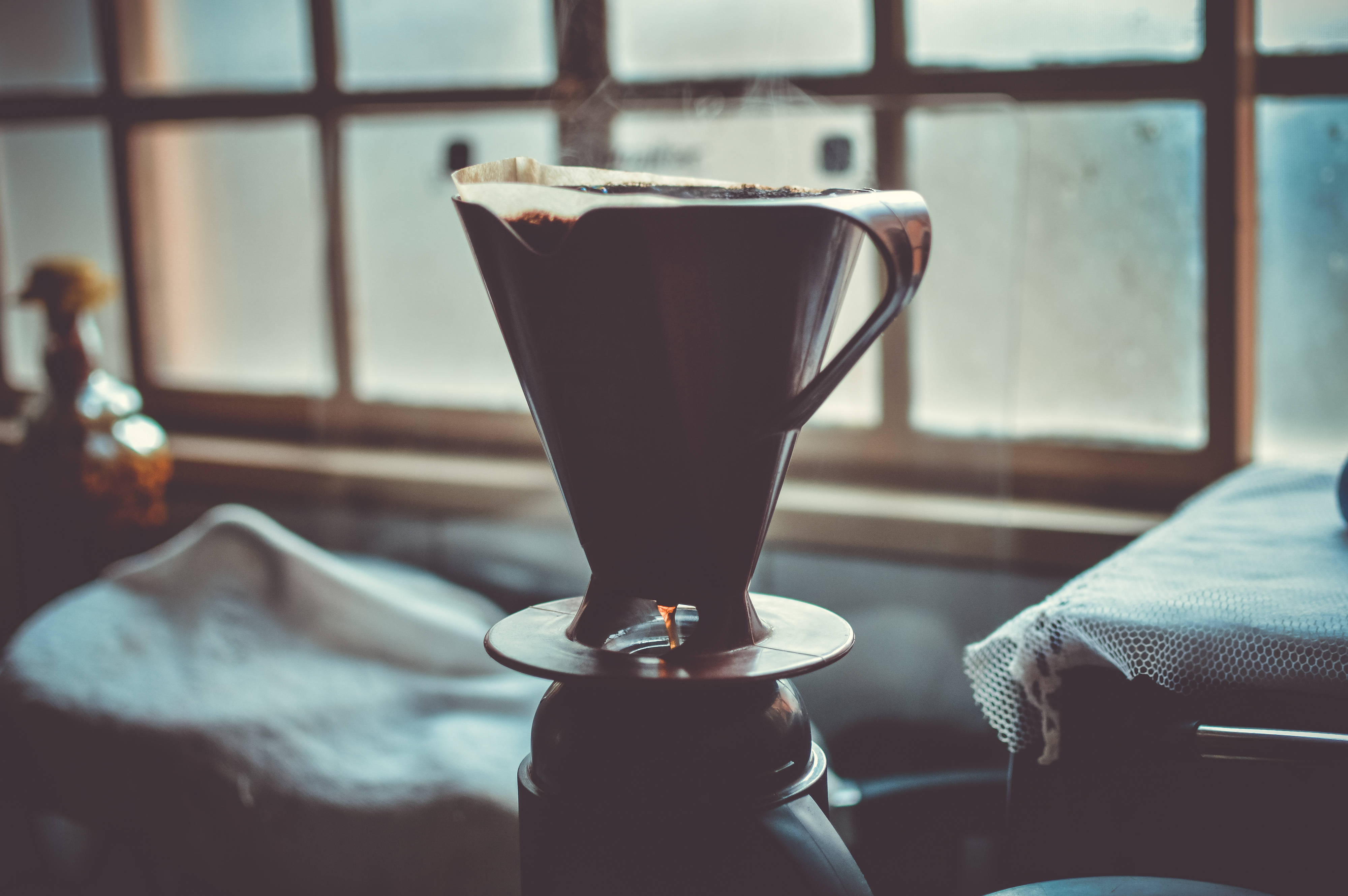 dark ceramic pour-over coffee dripper, glass carafe, sunlit window, 4K Desktop Wallpaper
