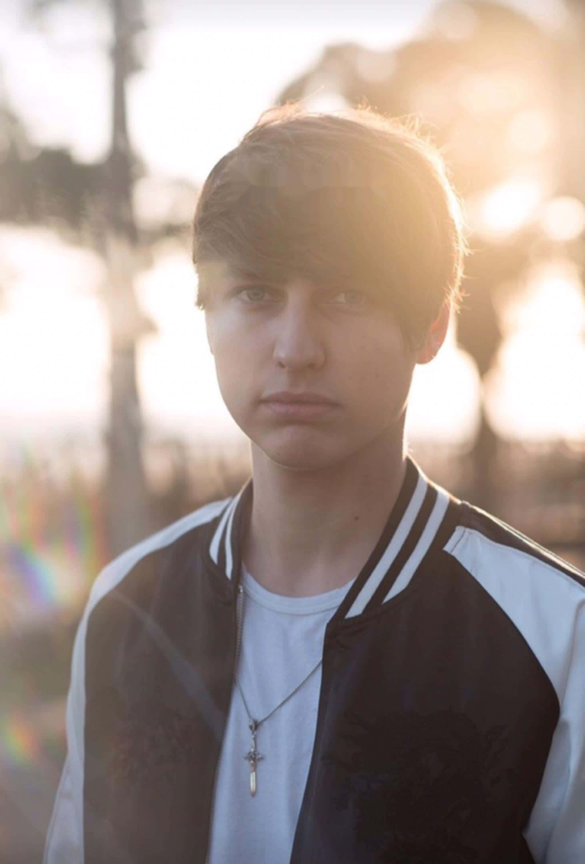 Colby Brock, black and white varsity jacket, golden backlighting, 2K Phone Wallpaper