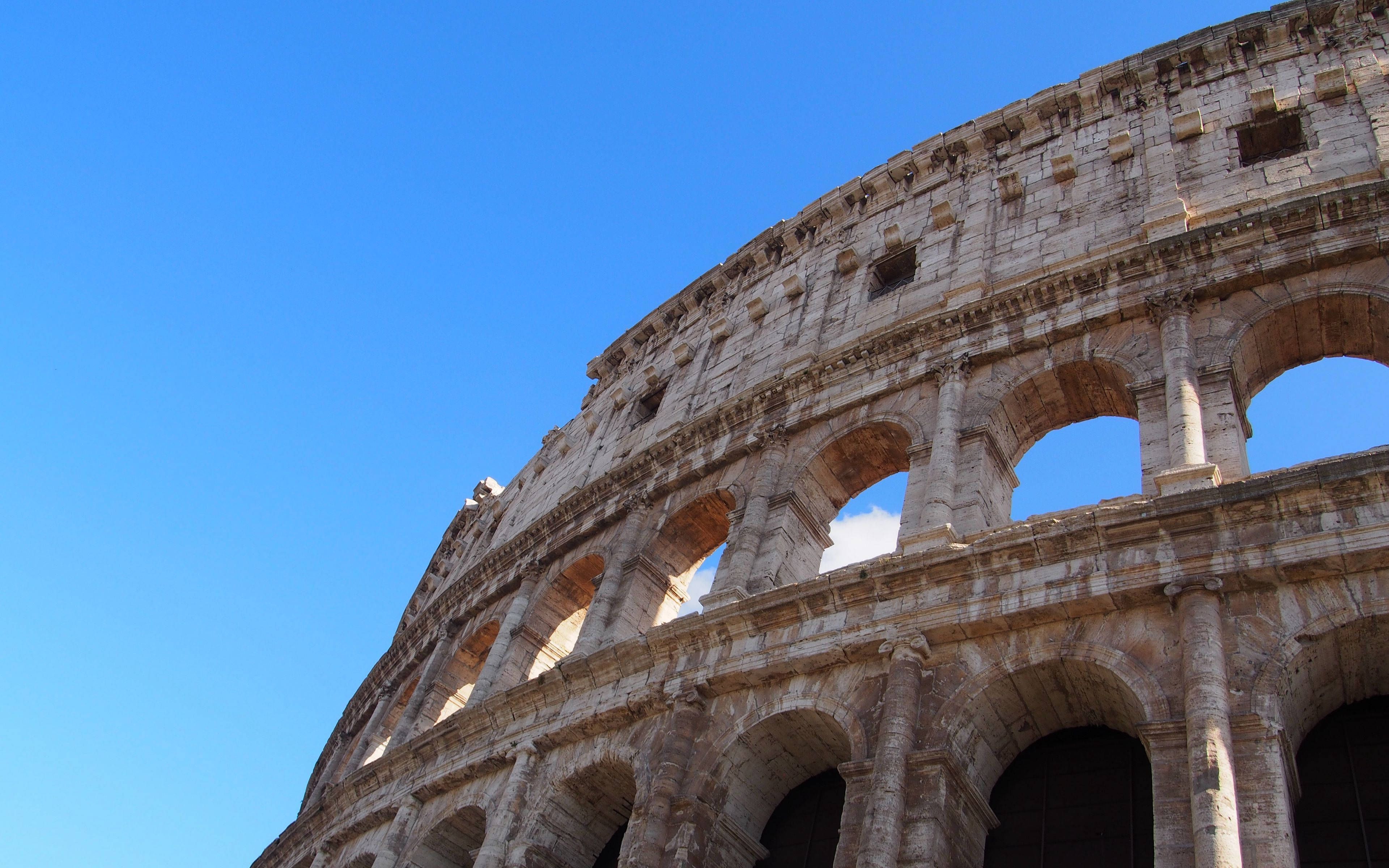 Colosseum, clear blue sky, sunlit stone arches, 4K Desktop Wallpaper