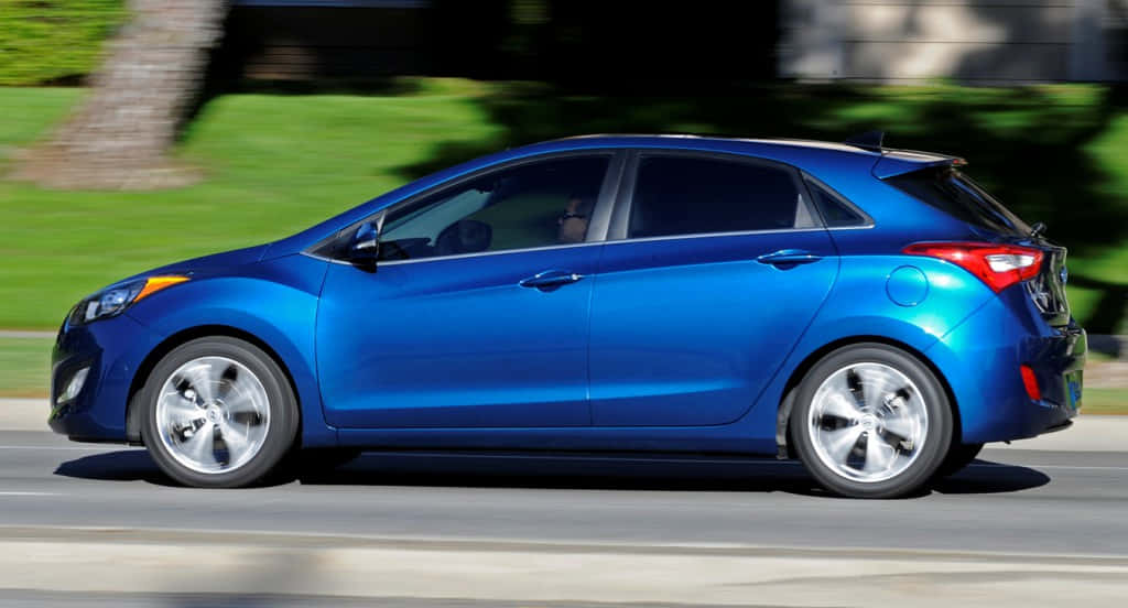 vibrant blue hatchback, sunlit road, blurred greenery, SD Desktop Wallpaper