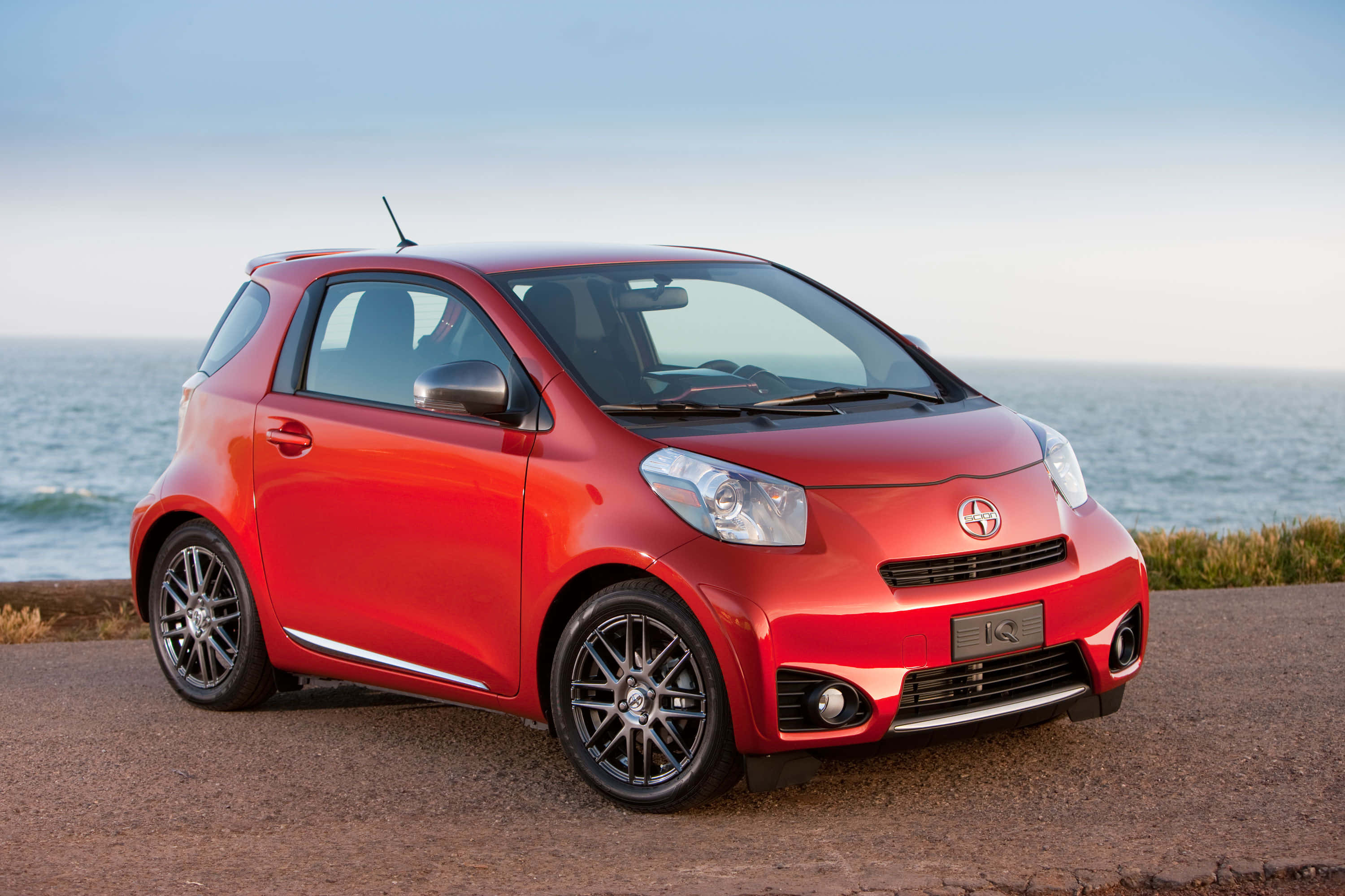 compact car, coastal road, ocean waves, 2K Desktop Wallpaper