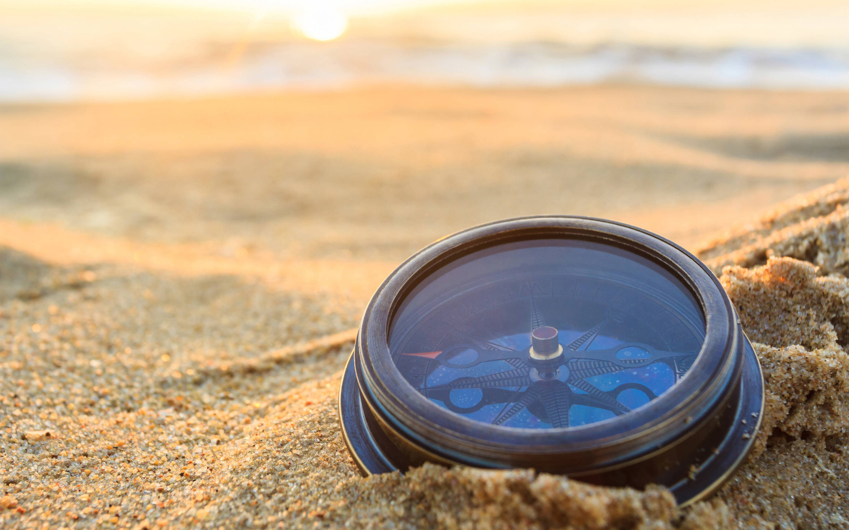 vintage compass, warm sand, golden sunset light, 2K Desktop Wallpaper