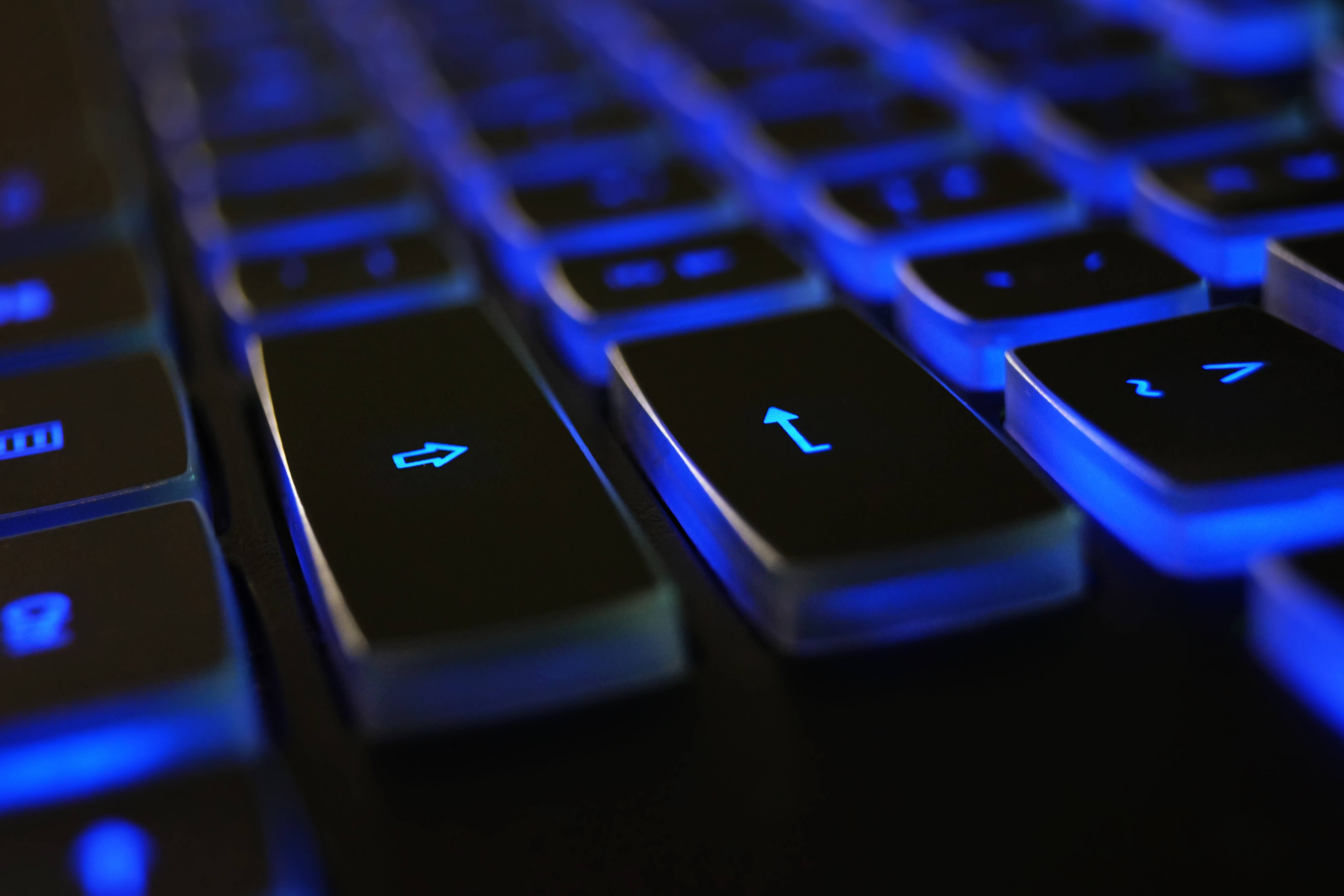 black keyboard, glowing blue arrow keys, dim lighting, 5K Desktop Wallpaper