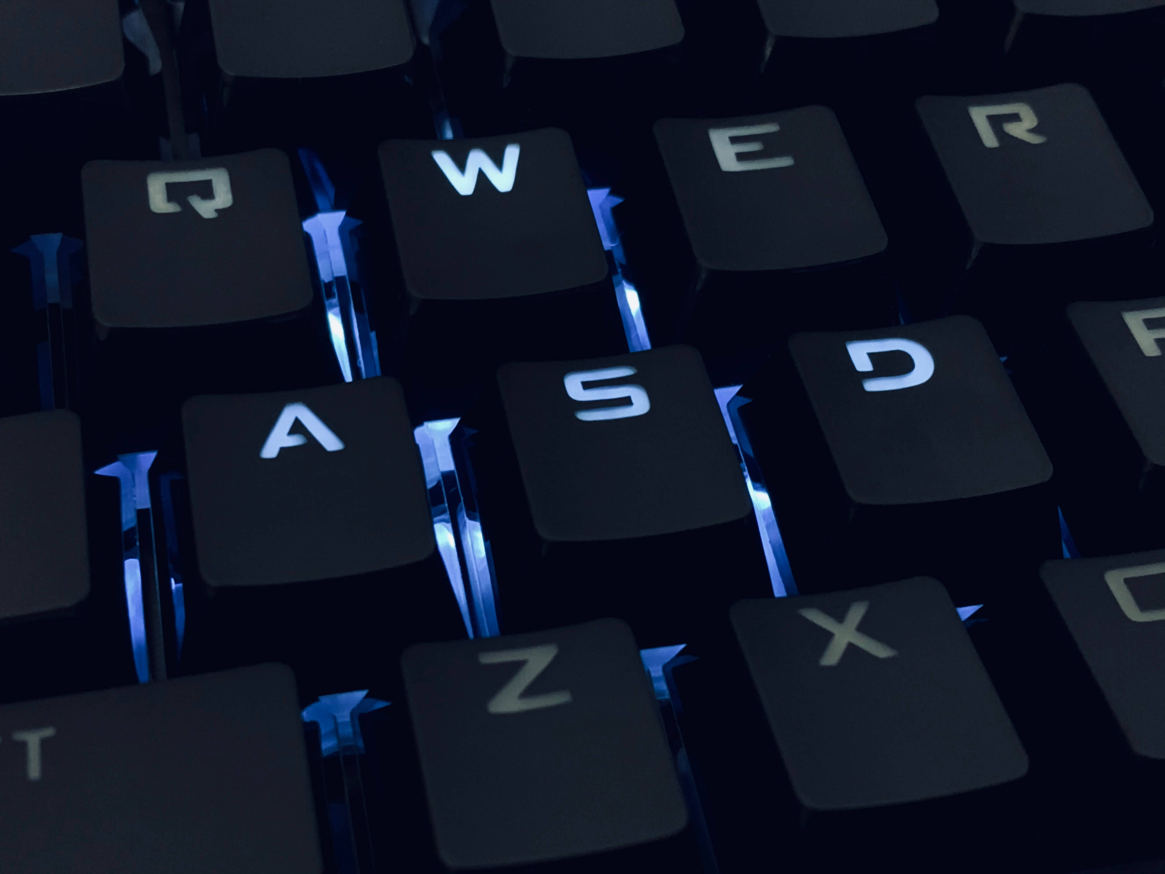 black mechanical keyboard, glowing blue backlighting, WASD keys, 4K Desktop Wallpaper