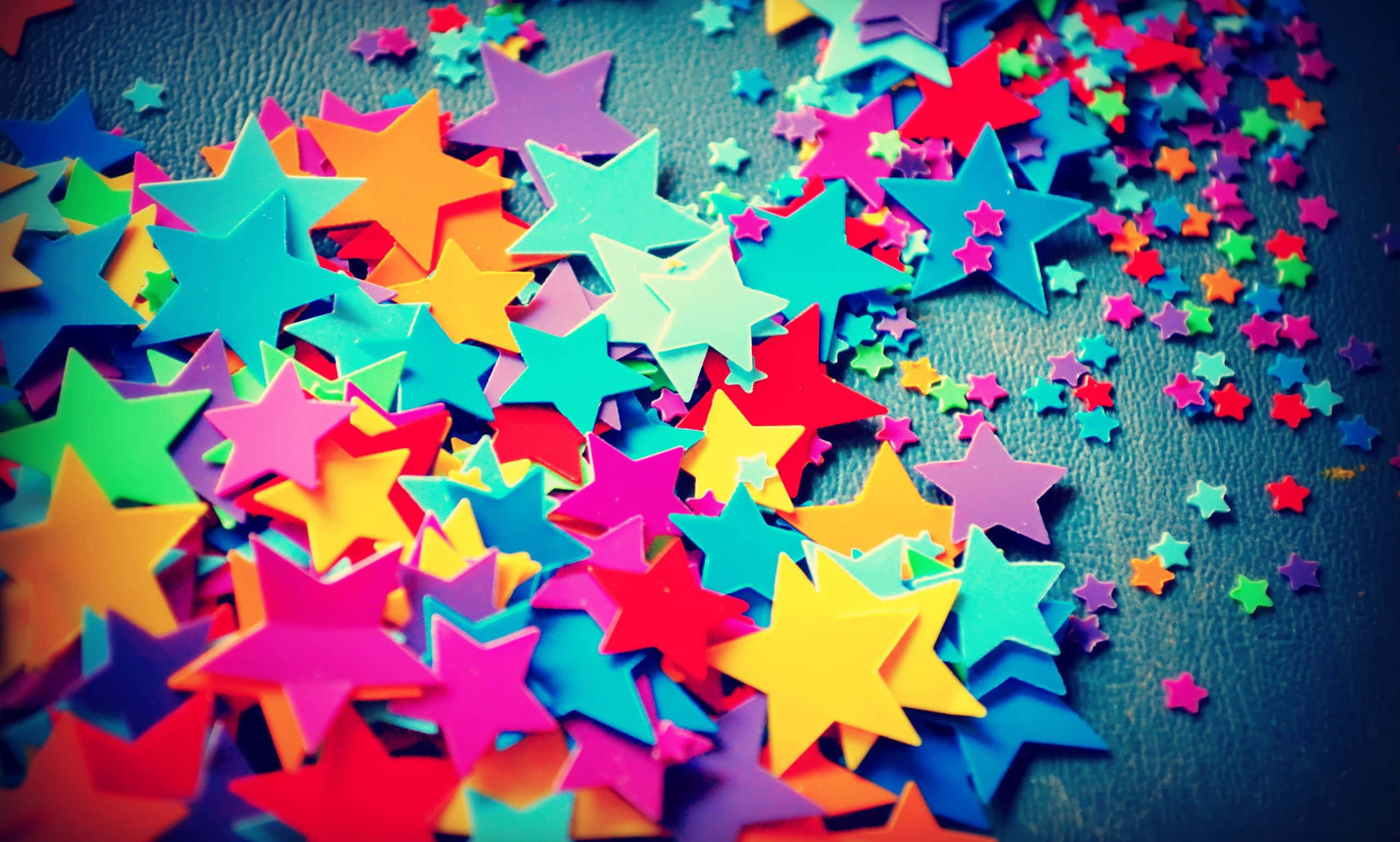 plastic star confetti, multicolored paper stars, textured dark blue surface, 2K Desktop Wallpaper