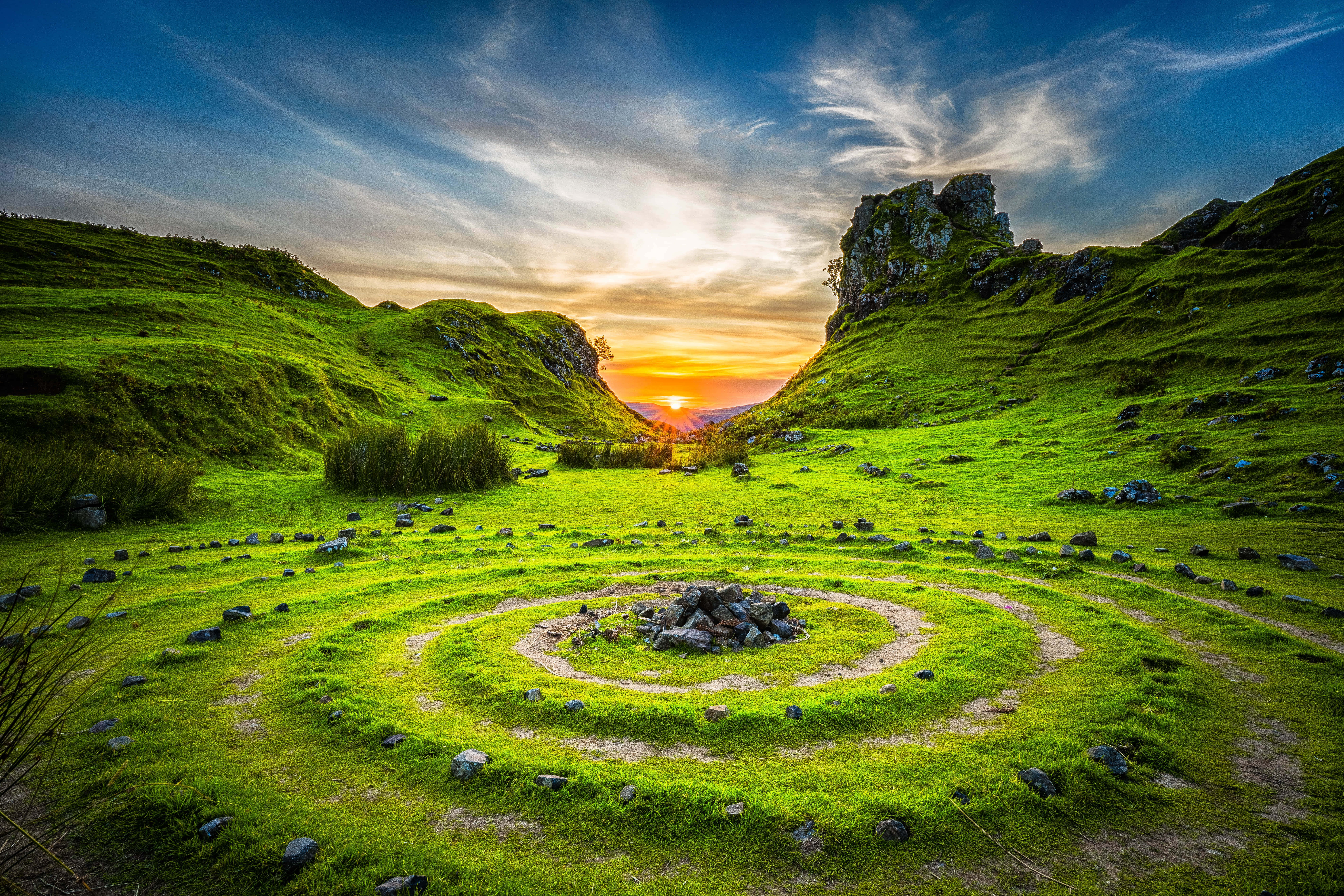 circular grassy field, rocks in the middle, vibrant green valley, 8K Desktop Wallpaper